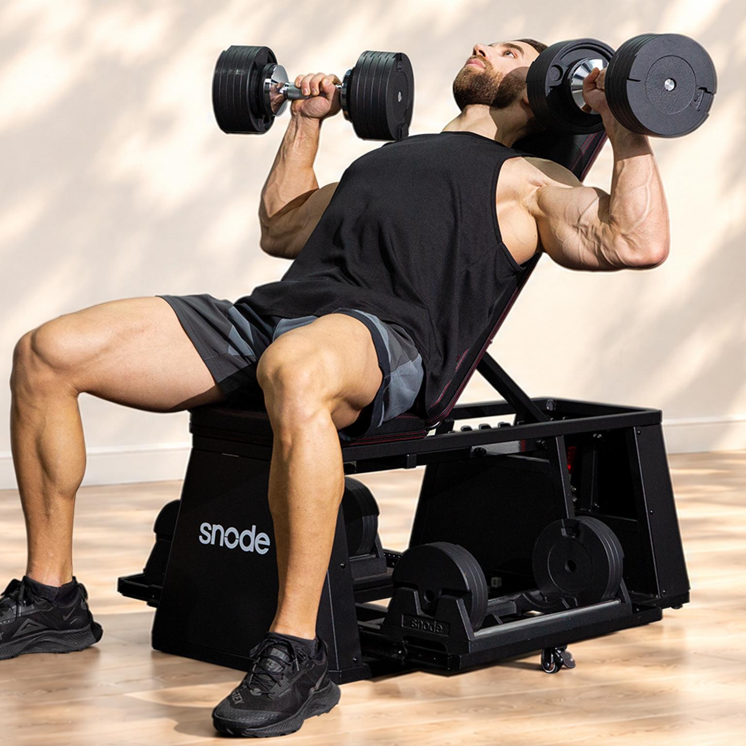 Muscular man doing incline dumbbell presses on a black Snod bench.