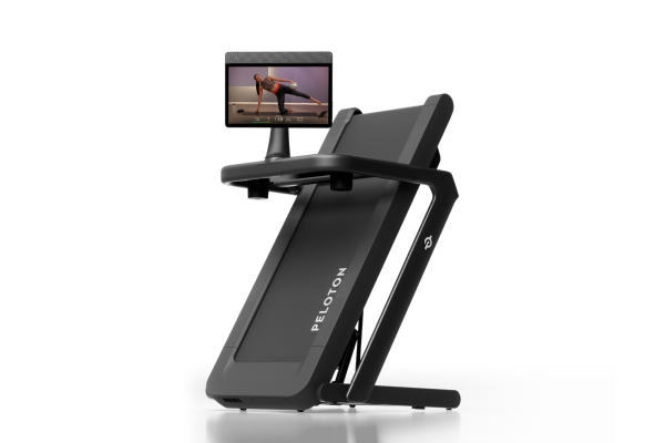 A dark grey Peloton Tread Flex from the side, with a screen showing a woman exercising.