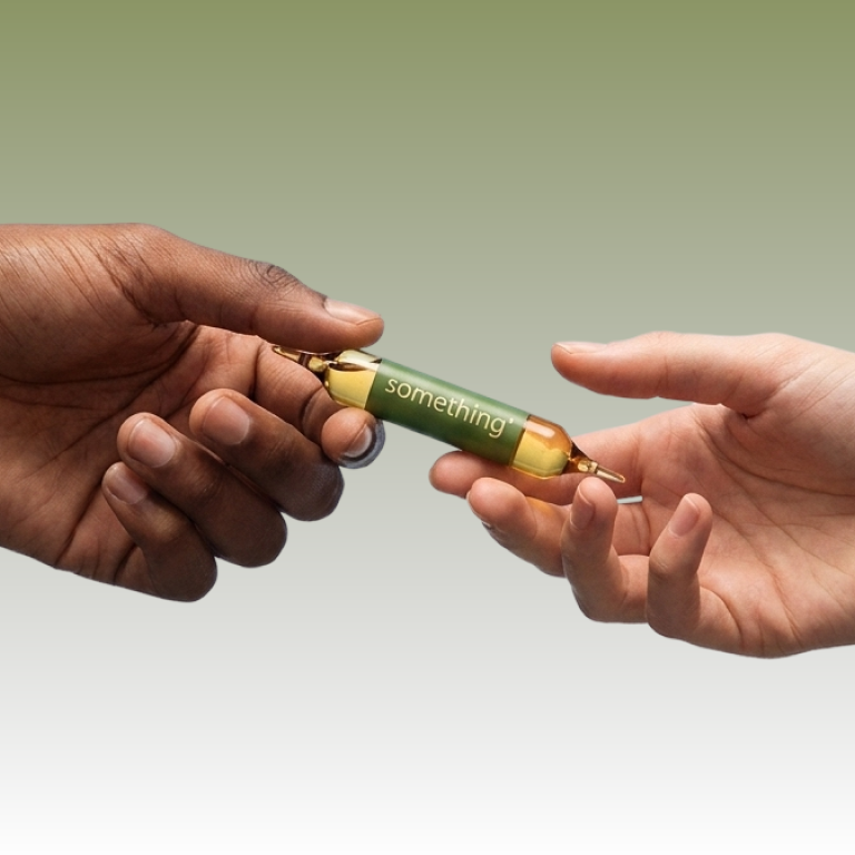 Two hands, one dark-skinned and one light-skinned, exchange a small glass vial labeled "something."