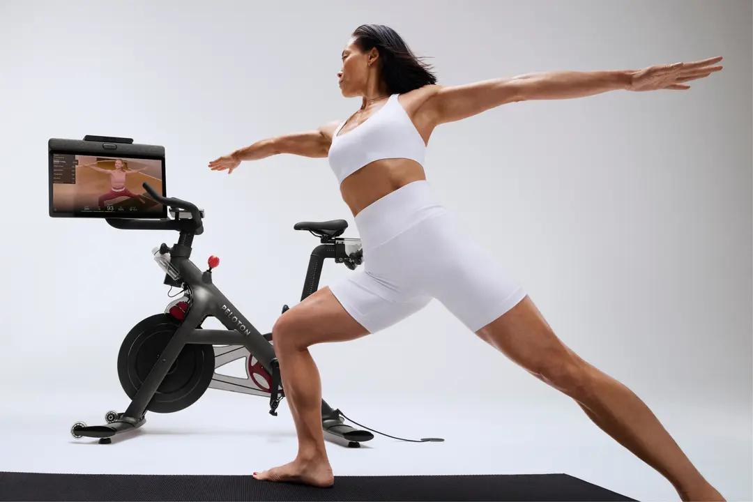 Woman working out using a Peloton program next to her Peloton bike