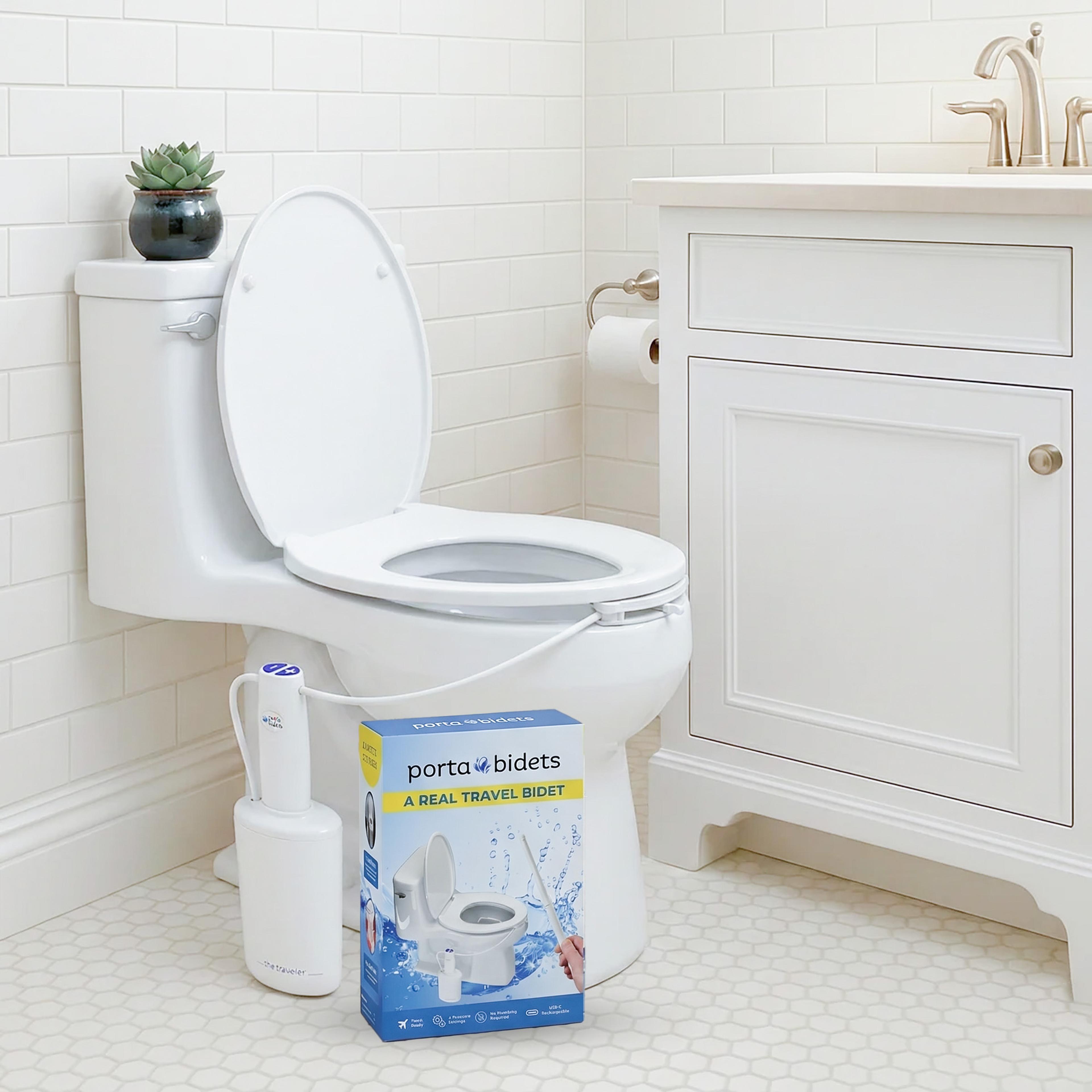 A toilet with a bidet attachment, next to a portable bidet device and a "Porta Bidets" product box in a white bathroom.