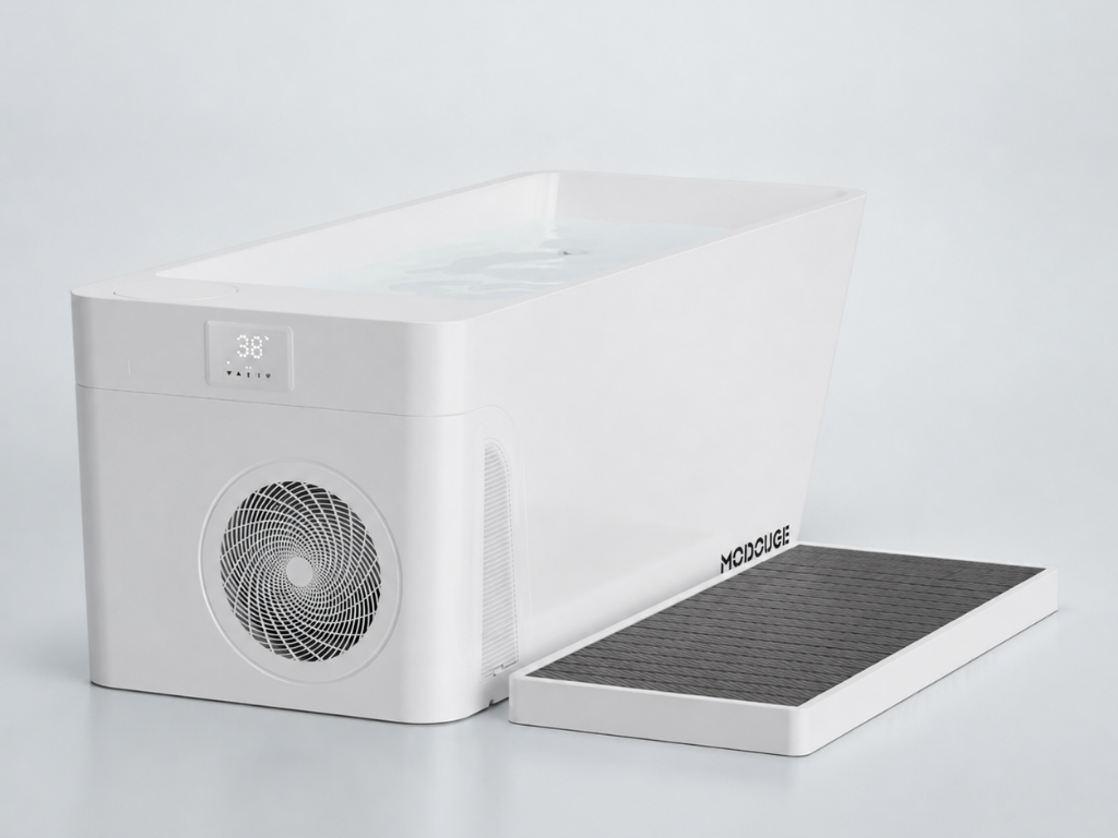 A white MODCUBE cold plunge tub filled with water, displaying "38°" on its screen, with a dark gray textured mat next to it.