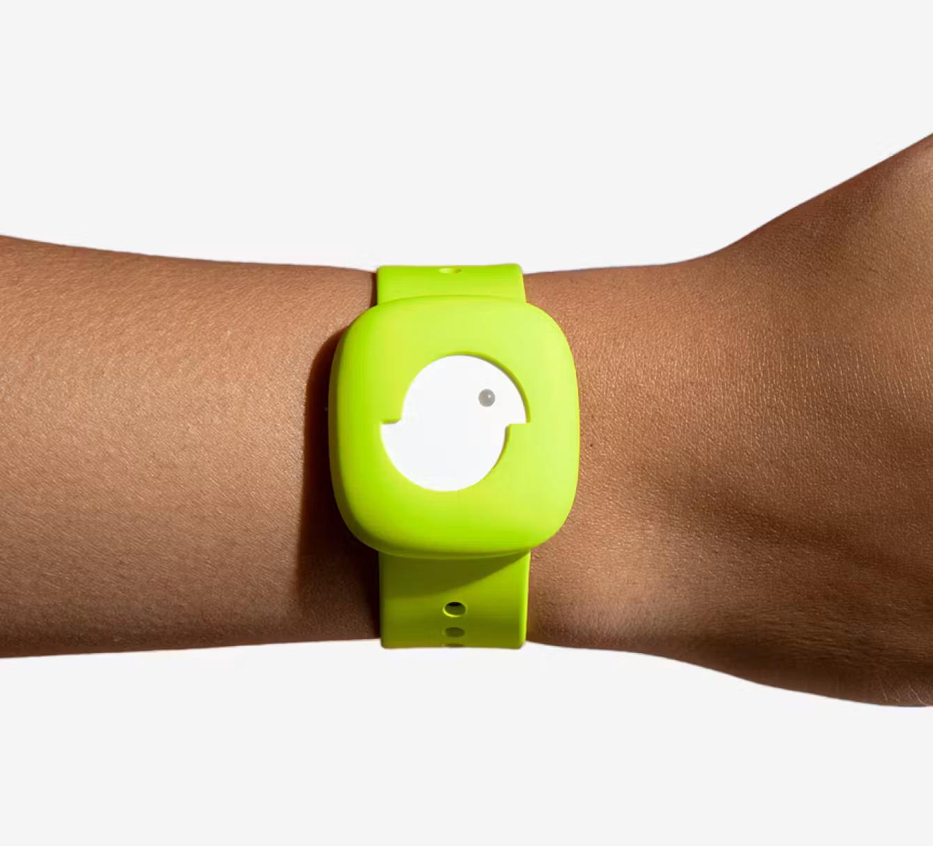 A bright green, rounded square device with a white bird-shaped face and a small dot for an eye, worn on a person's wrist.