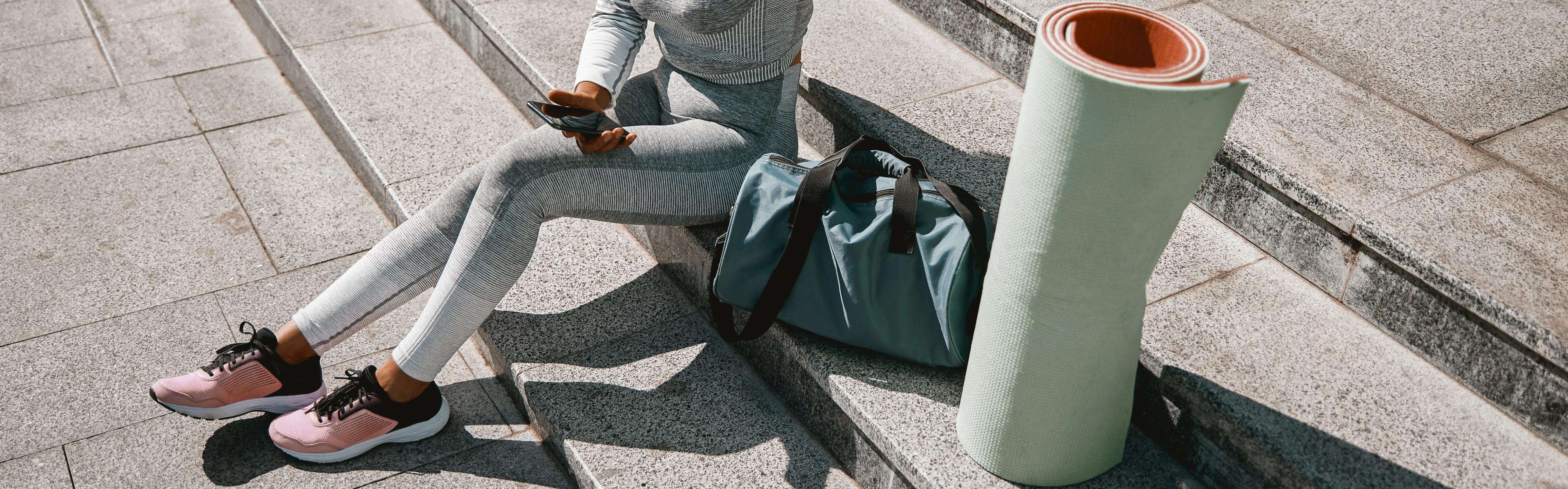 Woman sitting outside with yoga mat