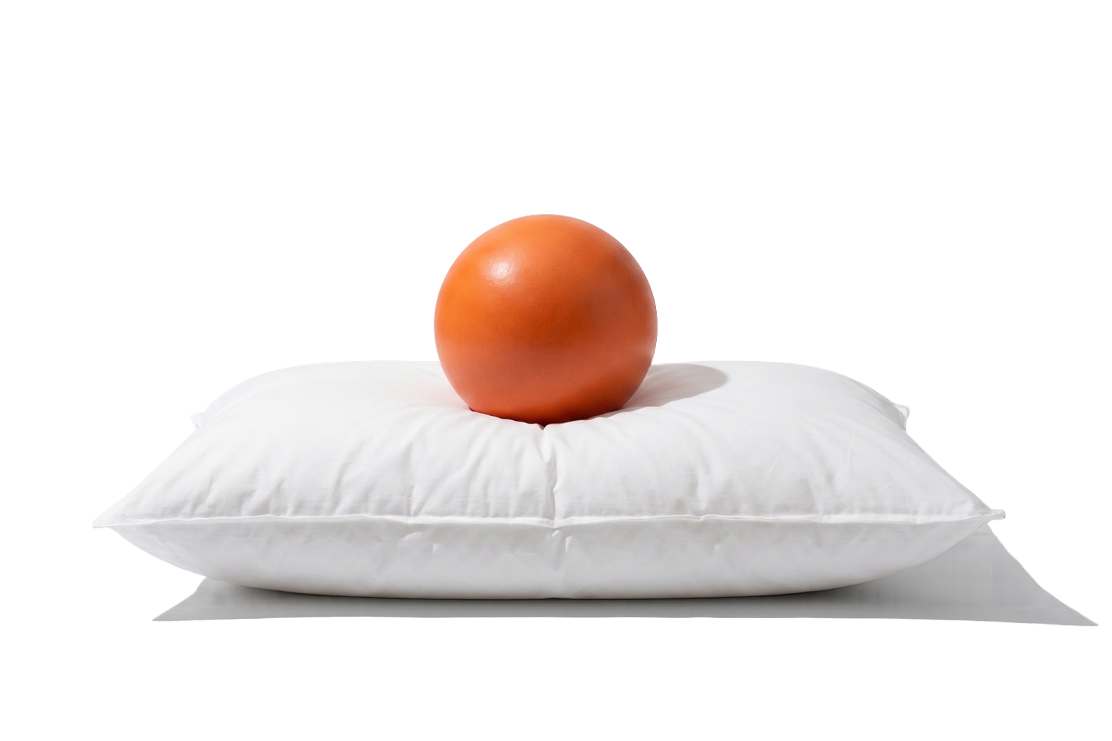 An orange ball resting on a white pillow.