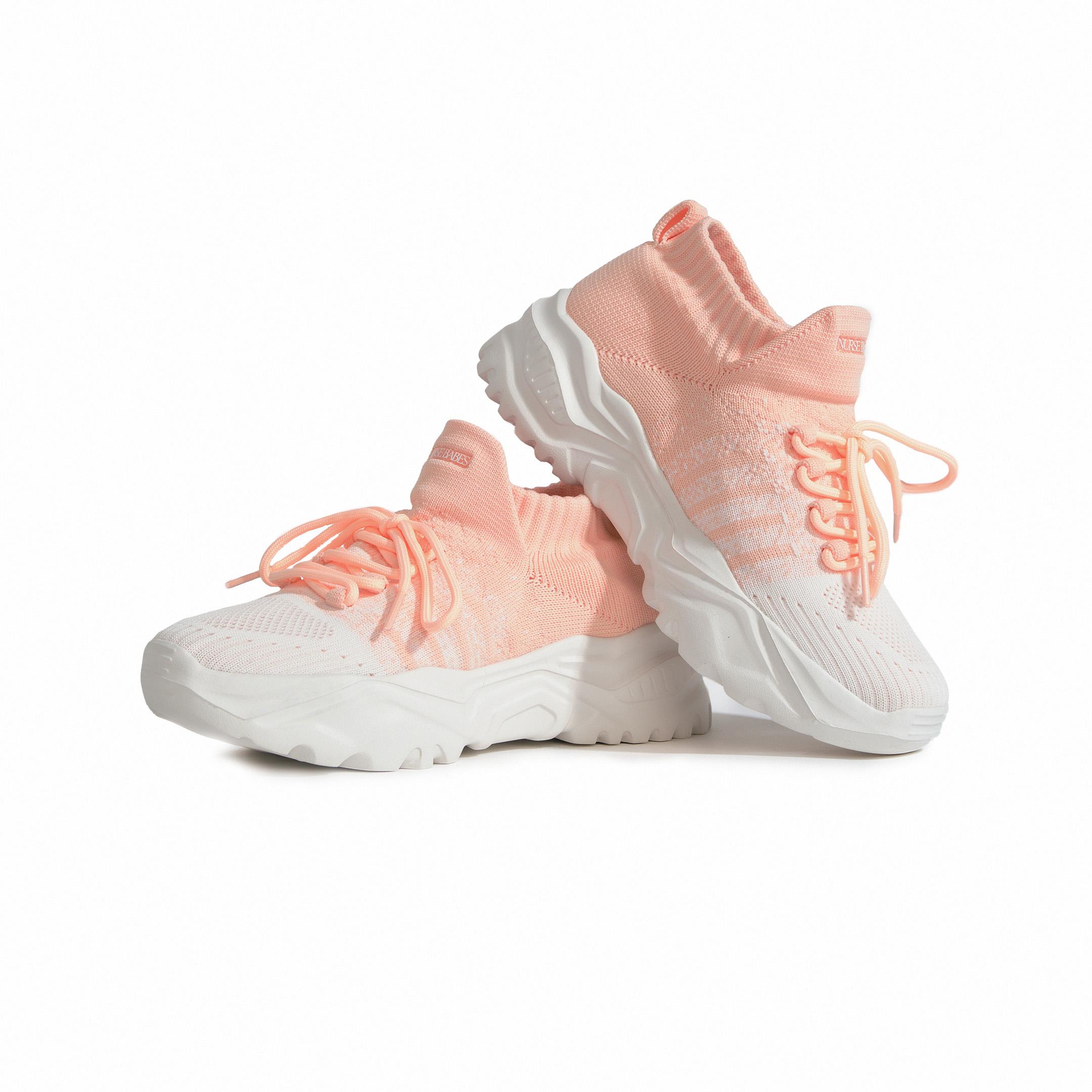 Pair of peach and white knit sneakers with chunky soles.