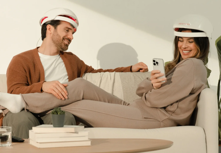 Couple sitting on couch wearing iRestore red light devices