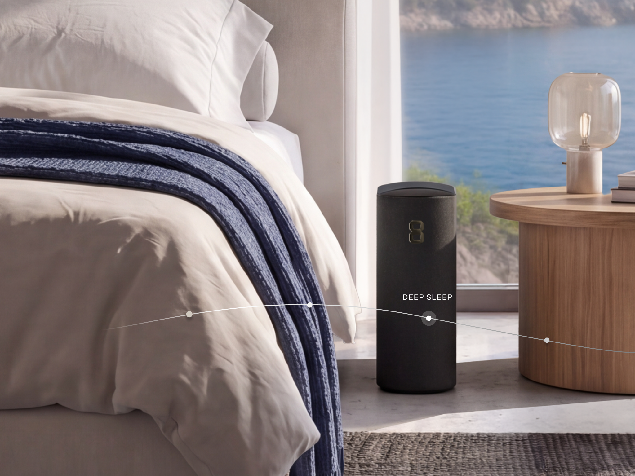A black "DEEP SLEEP" smart device sits on the floor beside a bed in a room overlooking the ocean.