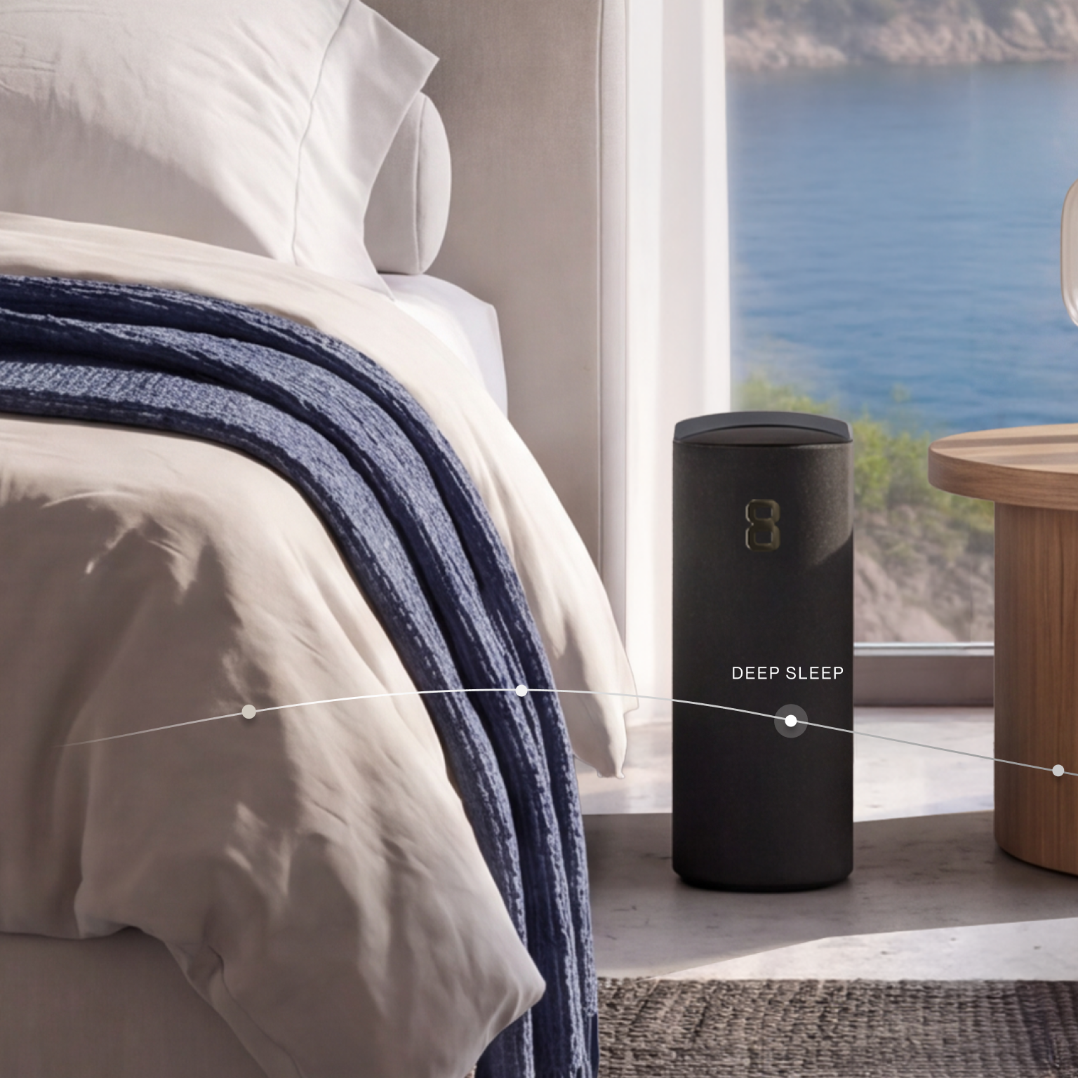 A black "DEEP SLEEP" smart device sits on the floor beside a bed in a room overlooking the ocean.