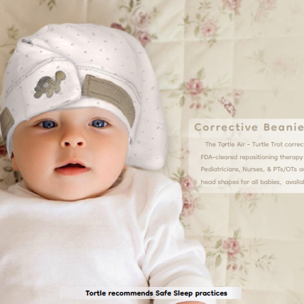 Baby wearing a white Tortie corrective beanie with a turtle emblem, lying on a floral blanket.