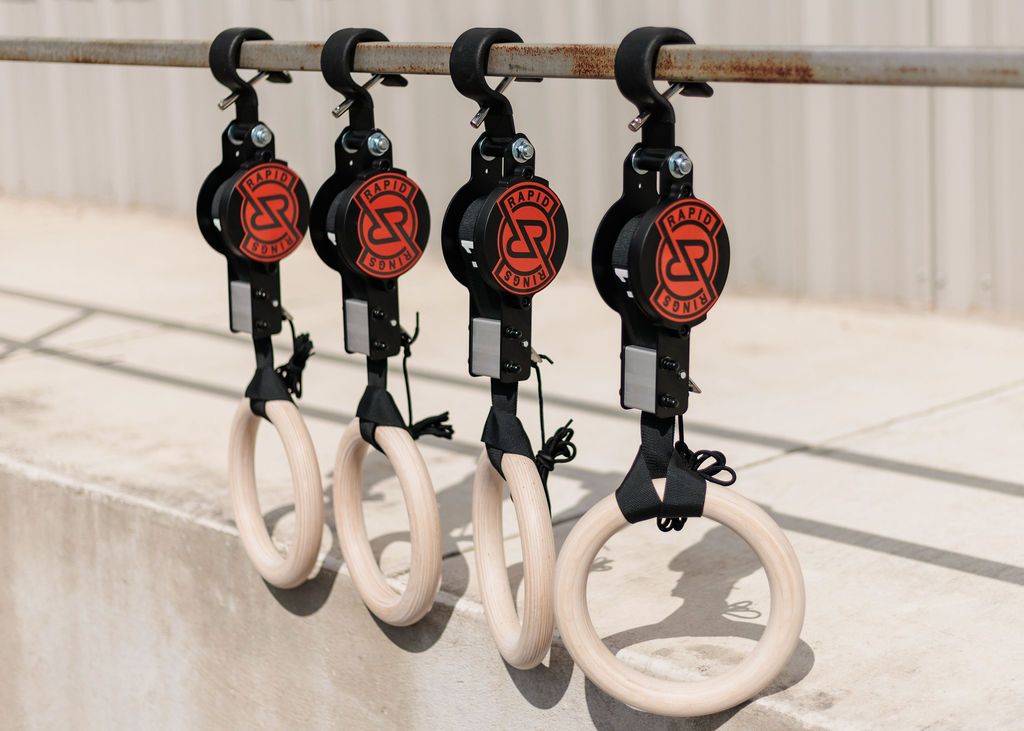 Four Rapid Rings brand wooden gymnastic rings hanging from a metal bar.