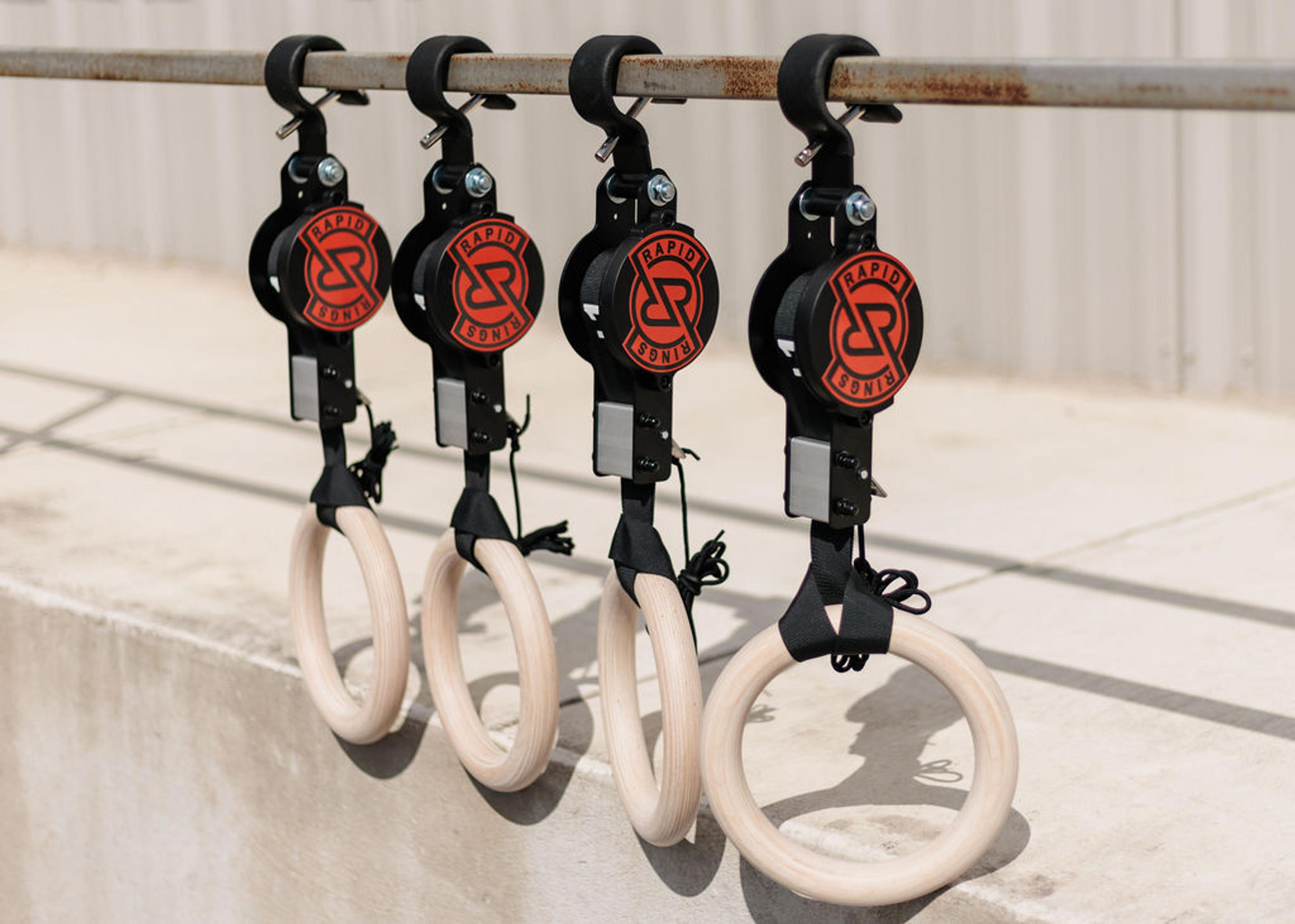 Four Rapid Rings brand wooden gymnastic rings hanging from a metal bar.