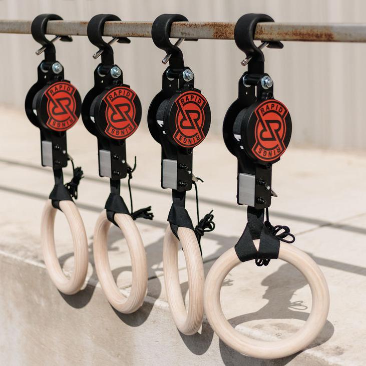Four Rapid Rings brand wooden gymnastic rings hanging from a metal bar.