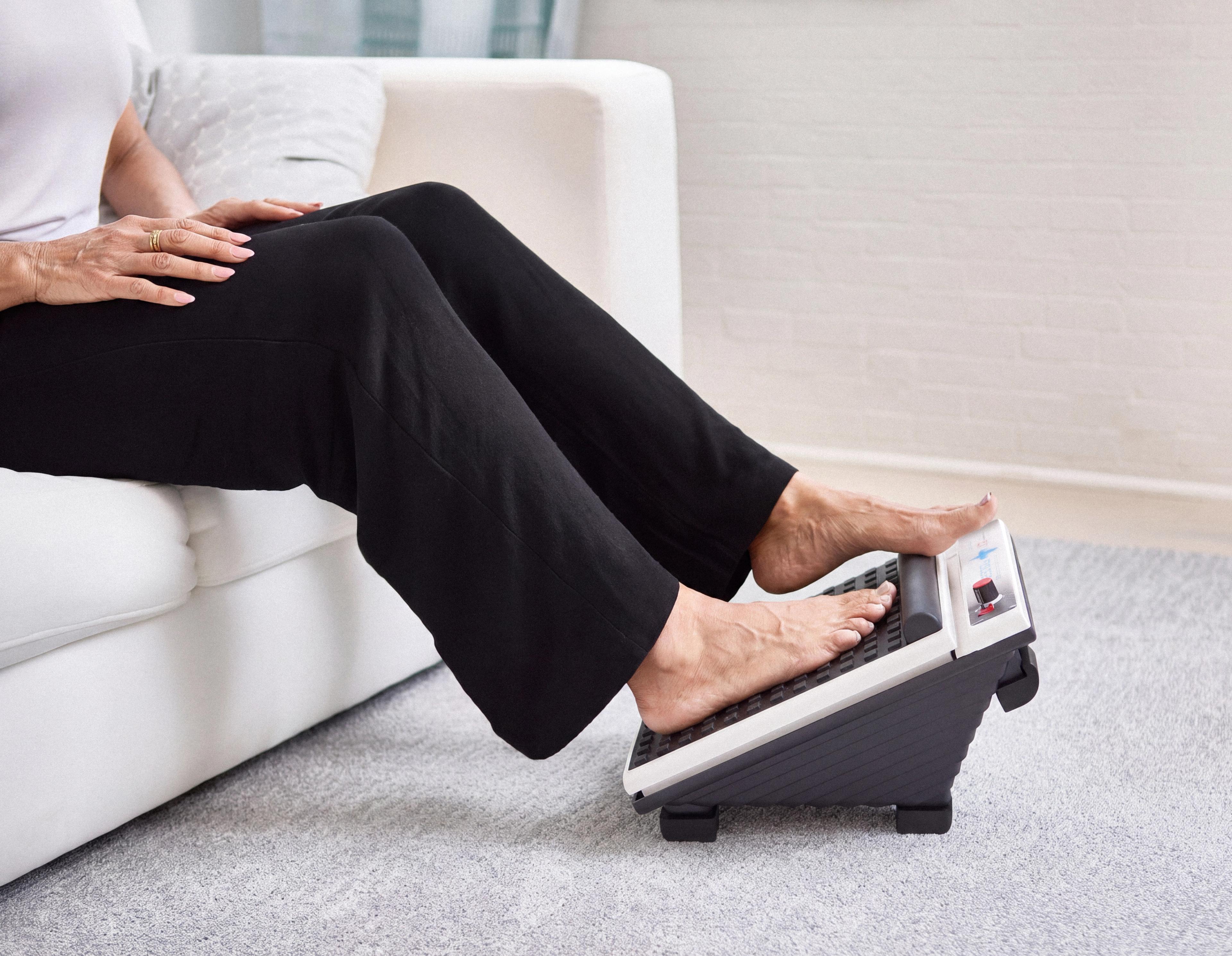 Bare feet on a foot massager with a fireplace in the background.
