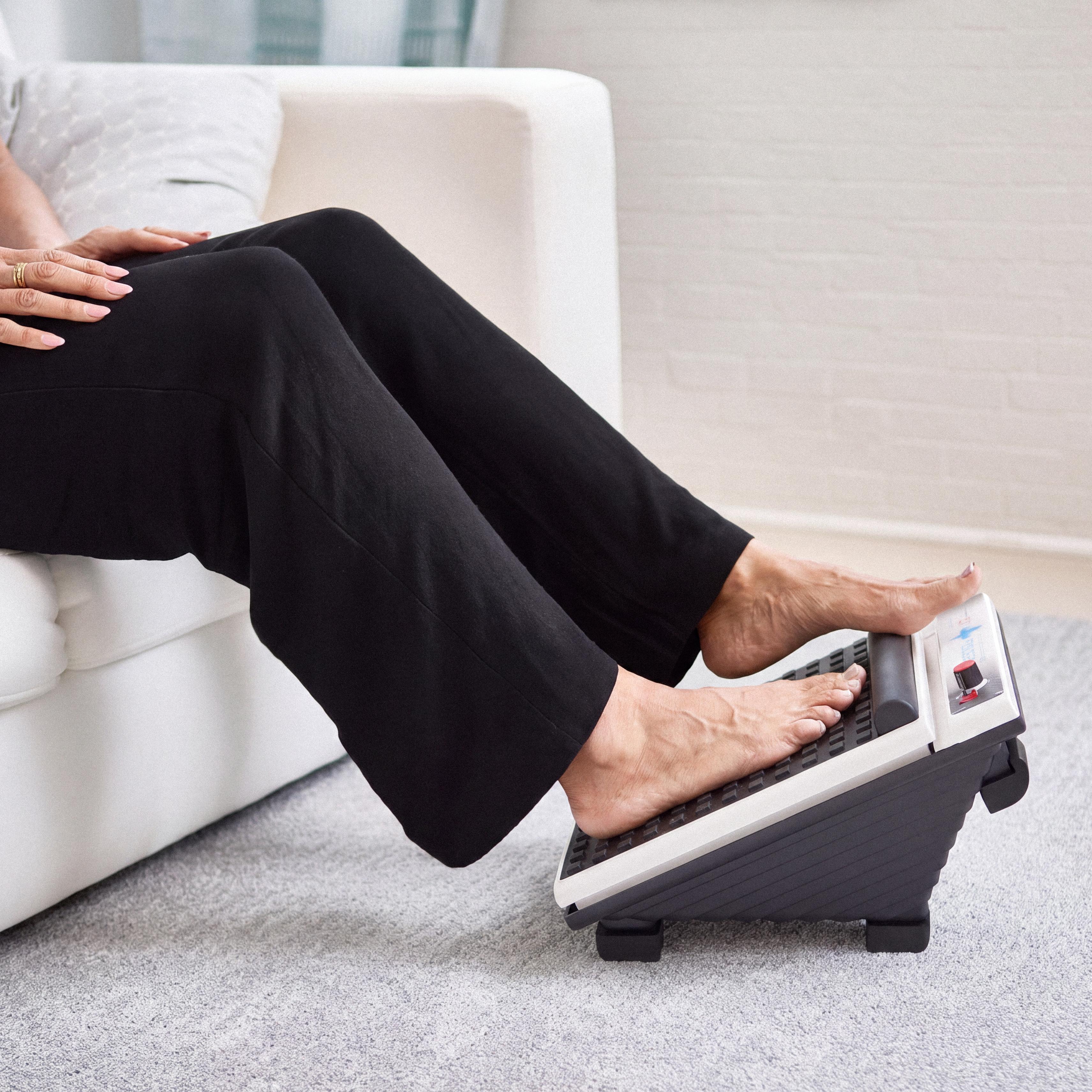 Bare feet on a foot massager with a fireplace in the background.