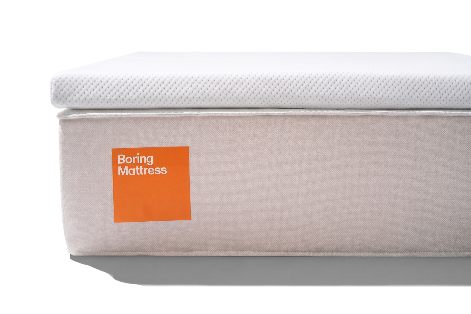 A white mattress with a beige side, featuring an orange label that reads "Boring Mattress".