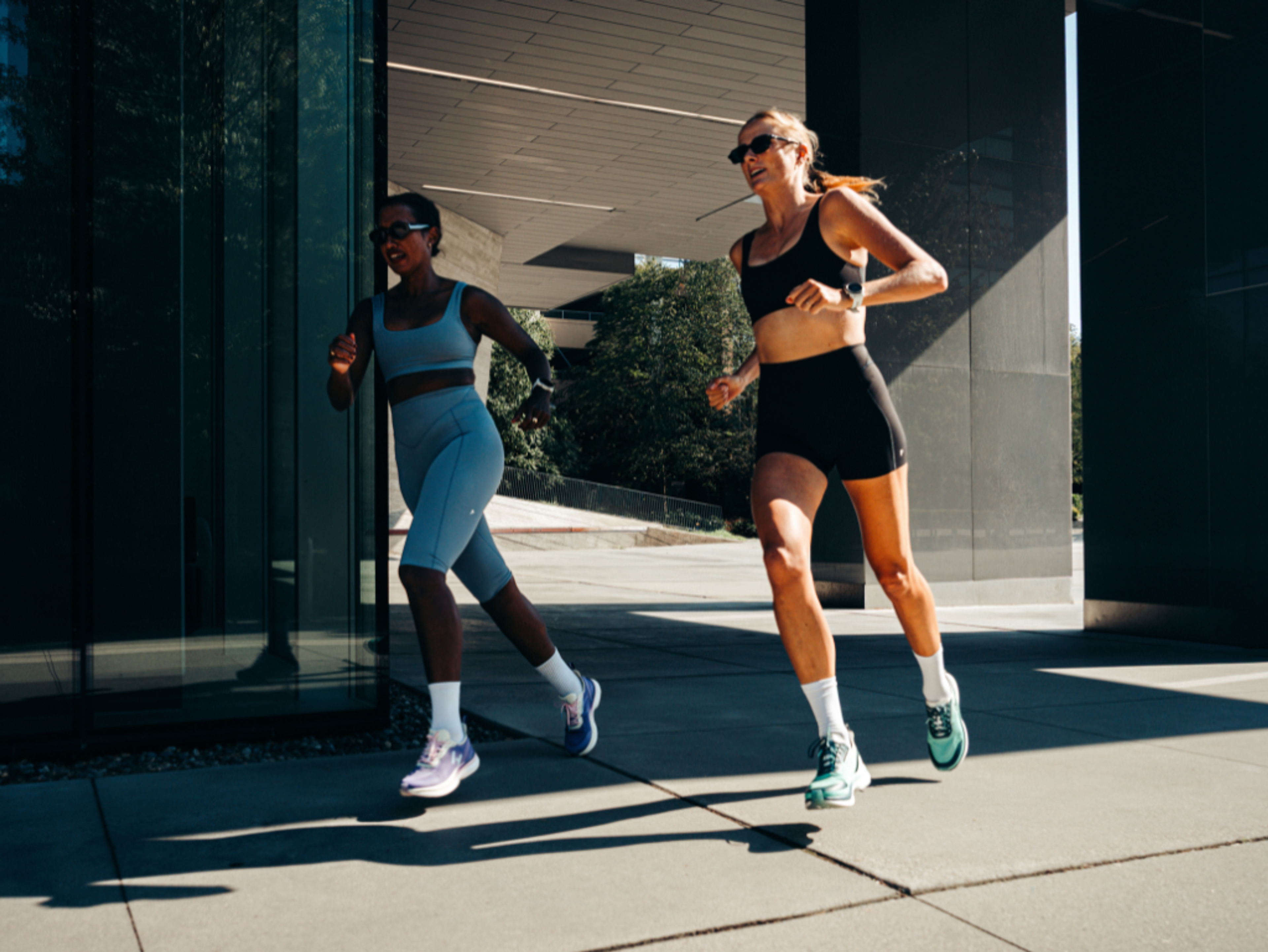Two women running outdoors in athletic wear.