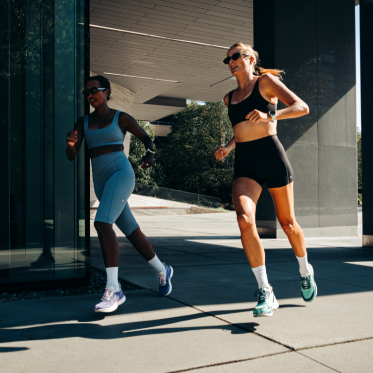 Two women running outdoors in athletic wear.