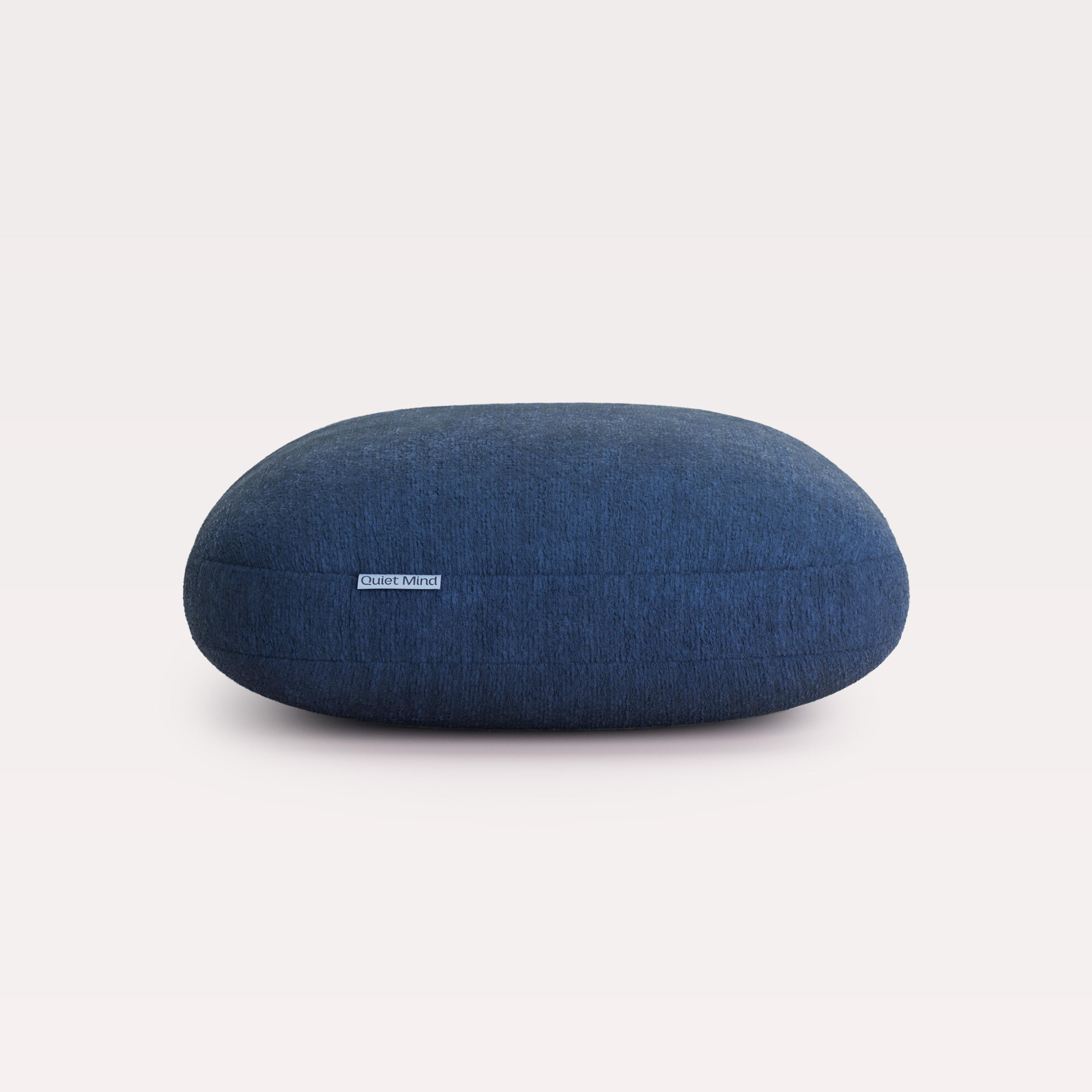 Dark blue oval cushion with a 'Quiet Mind' label.