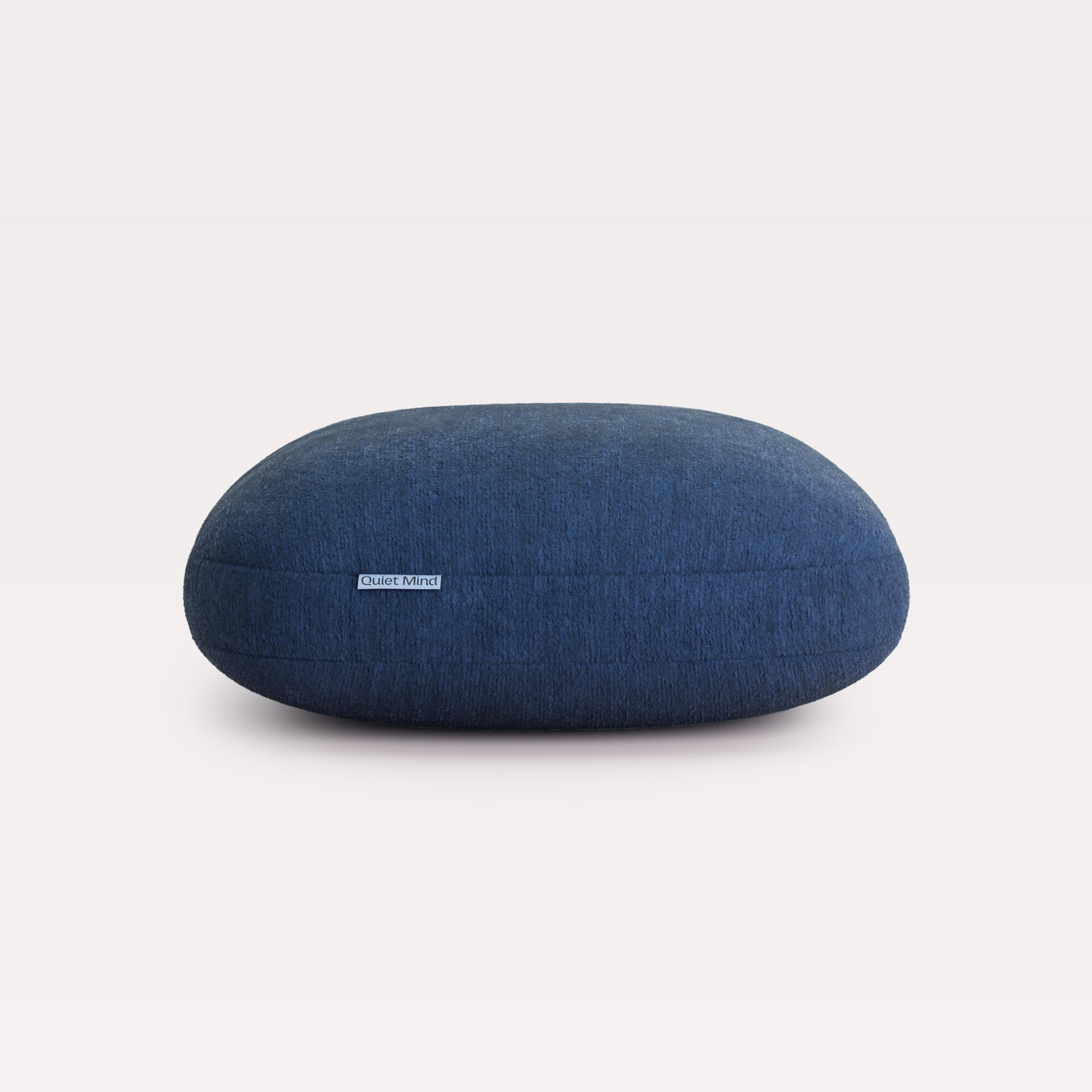 Dark blue oval cushion with a 'Quiet Mind' label.