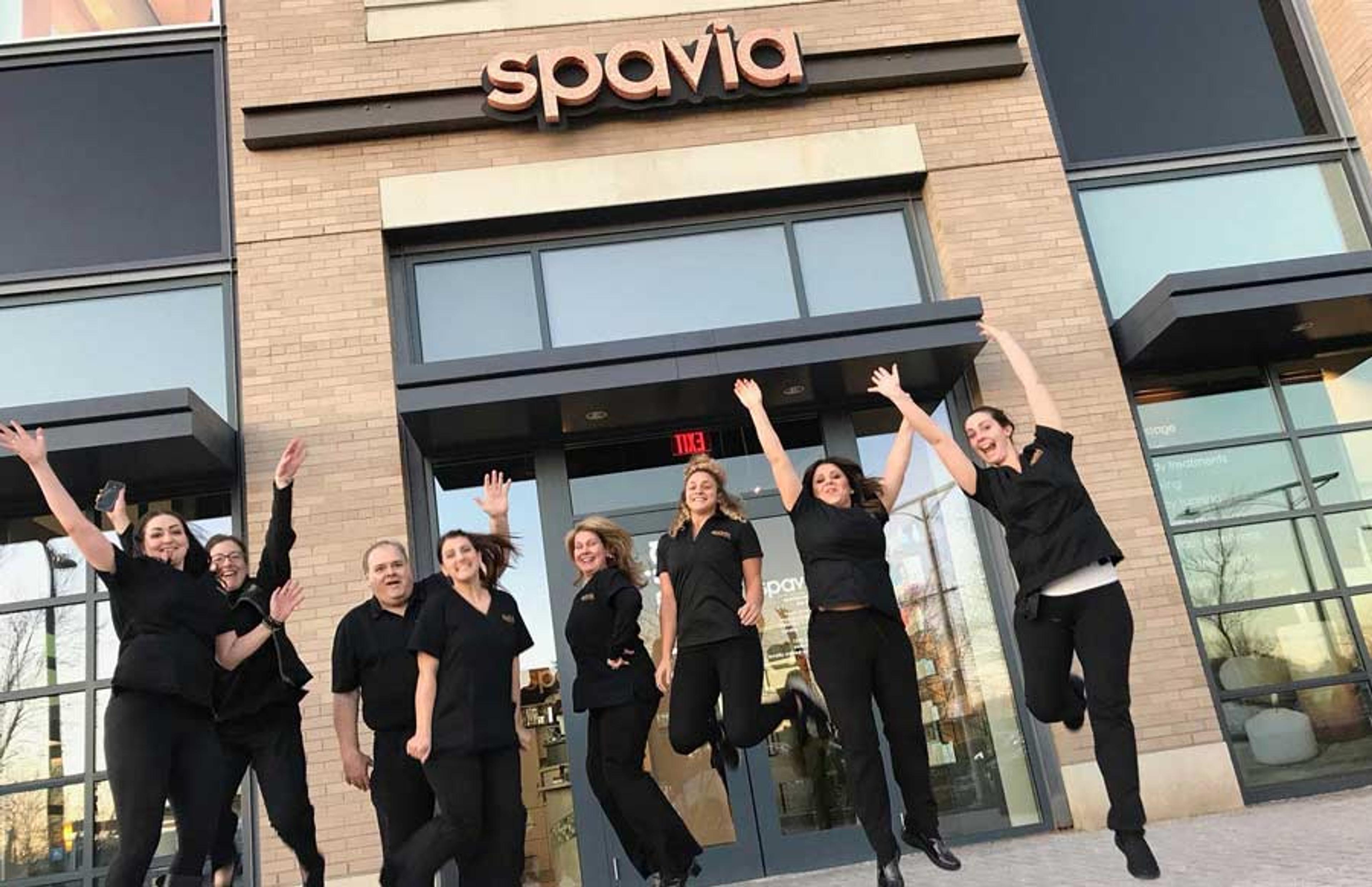 Happy Spavia staff jumping in front of the spa entrance.