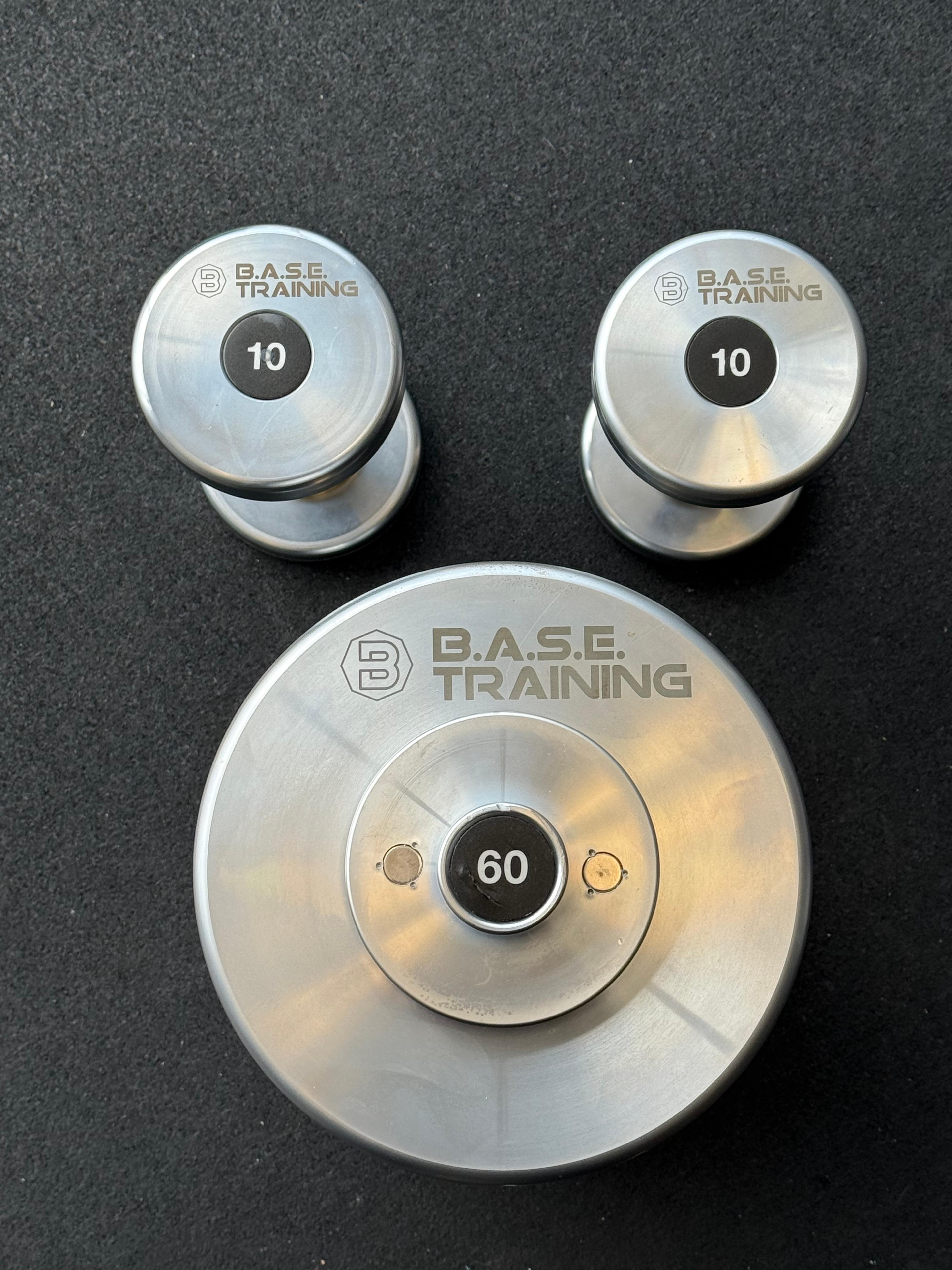Two 10lb and one 60lb B.A.S.E. Training dumbbells on a dark surface.