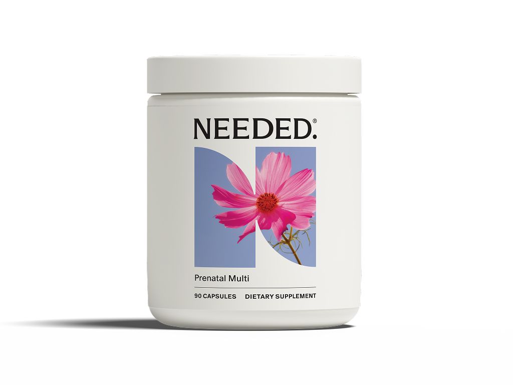 White jar of Needed. Prenatal Multi, a dietary supplement with 90 capsules. The label features a pink cosmos flower on a blue background, forming the letter 'N'.