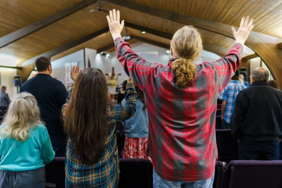 A man and woman raising their hands in worship at the Ridge Bible Church in Graham, Wa.