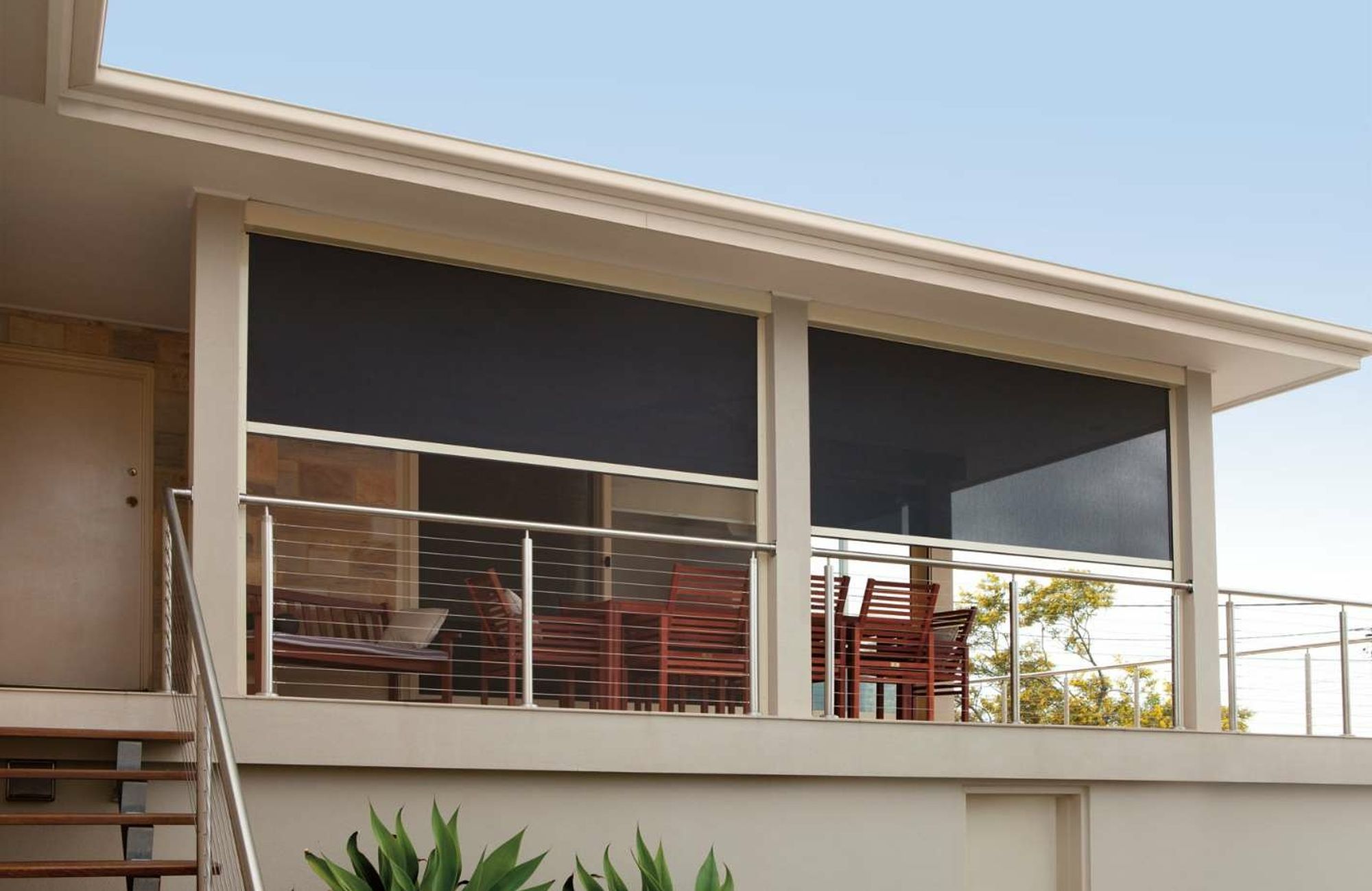 Dark mesh Zipscreen outdoor blinds partly lowered across an elevated balcony