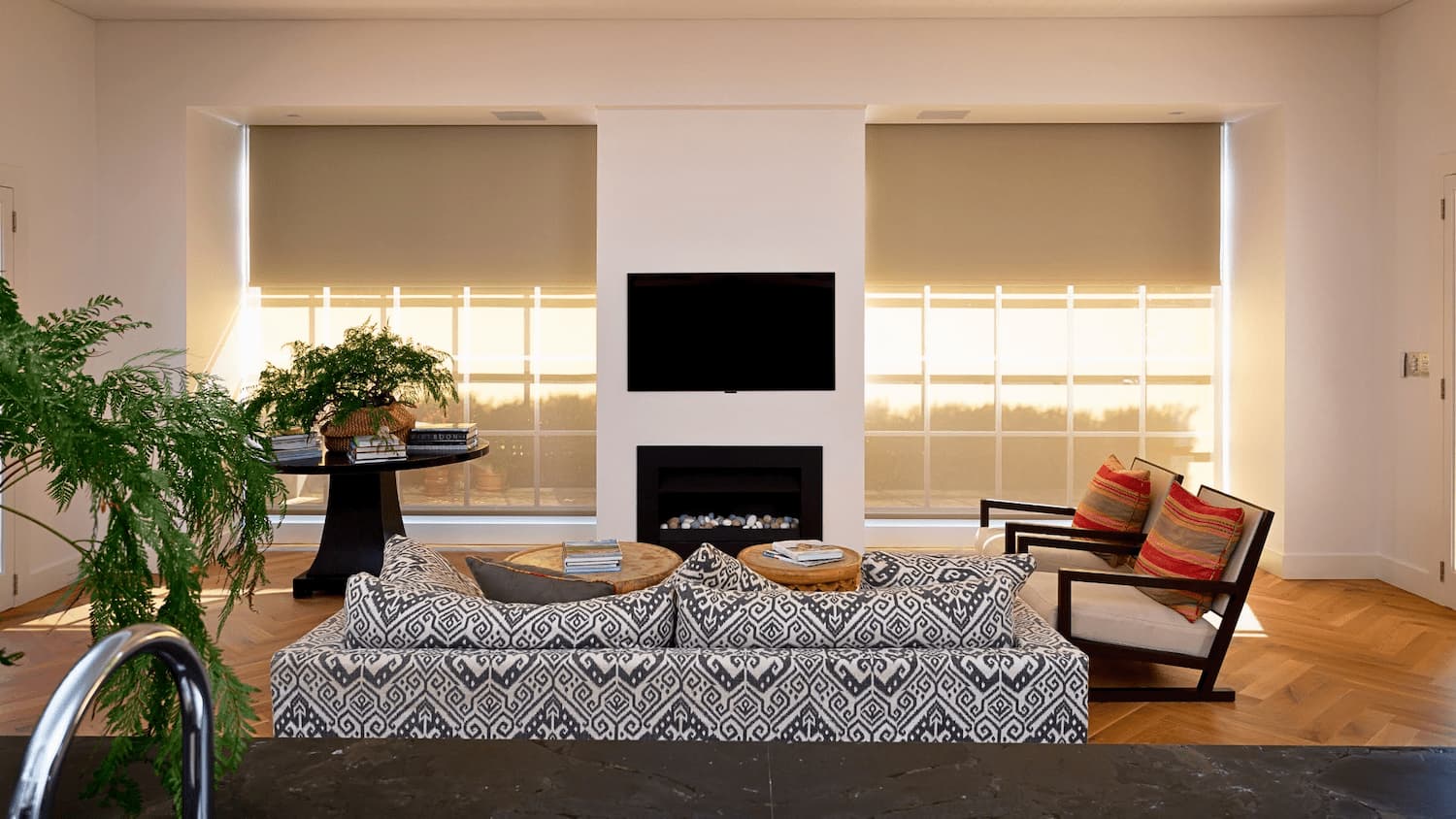 Two motorised roller blinds either side of a fireplace