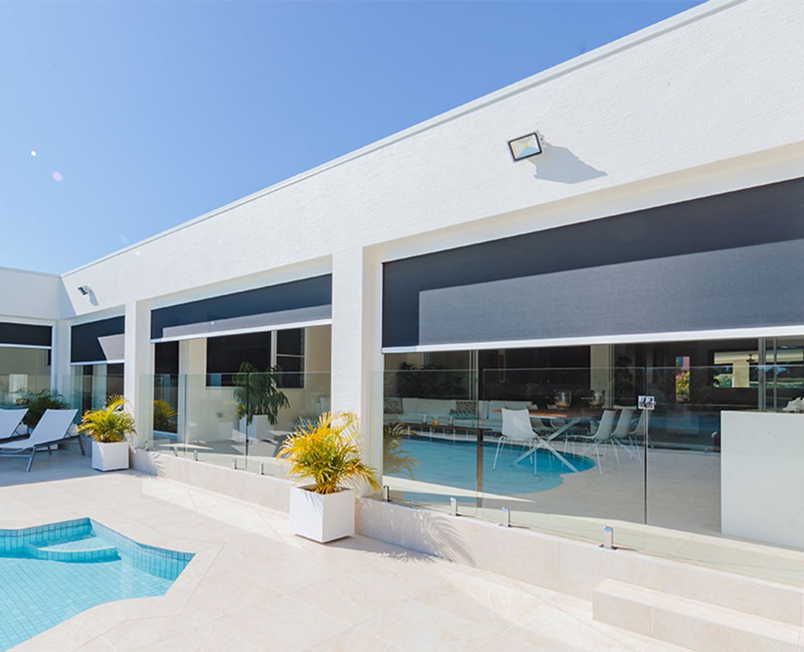 Dark outdoor blinds in side channels shading a poolside alfresco area