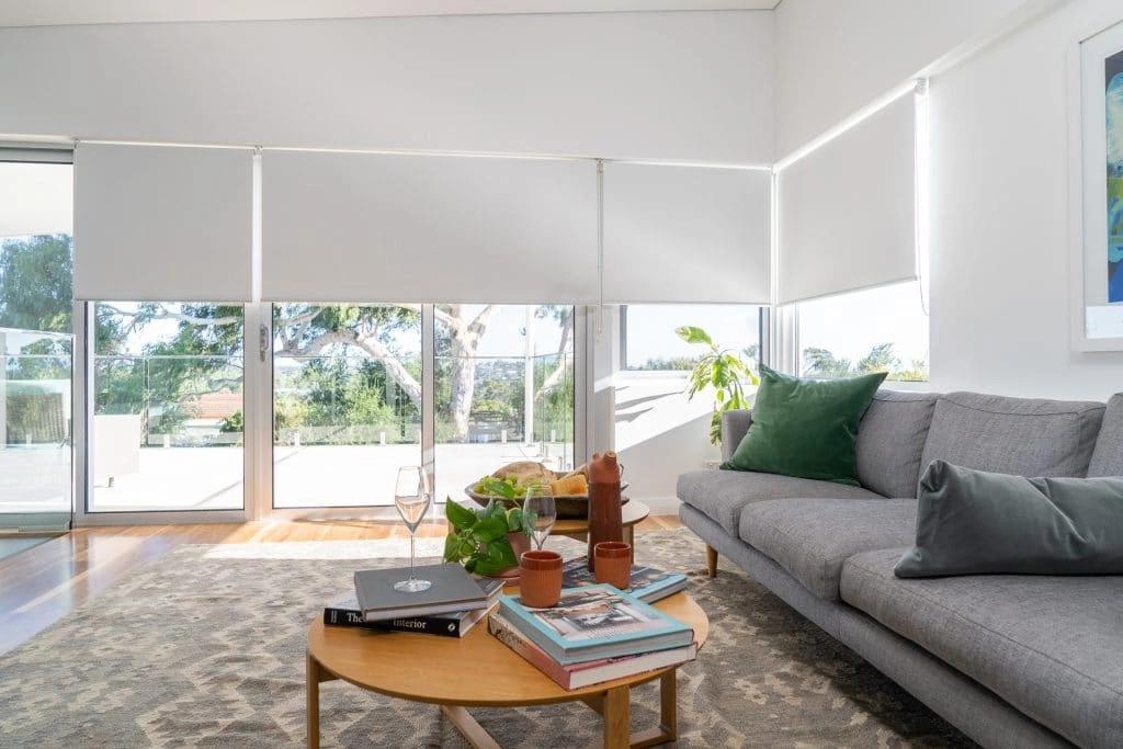 White roller blinds lowered over the living room windows