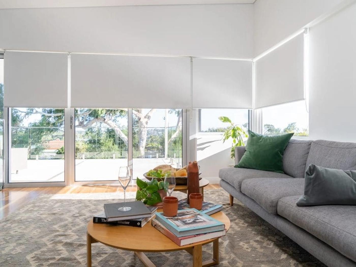 White roller blinds lowered over the living room windows