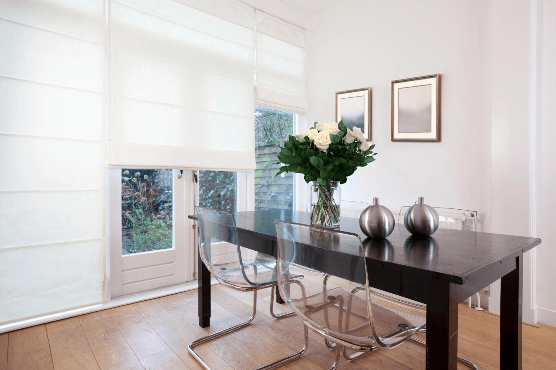 Norman Roman shades in crisp white fabric across tall windows in a bright dining room