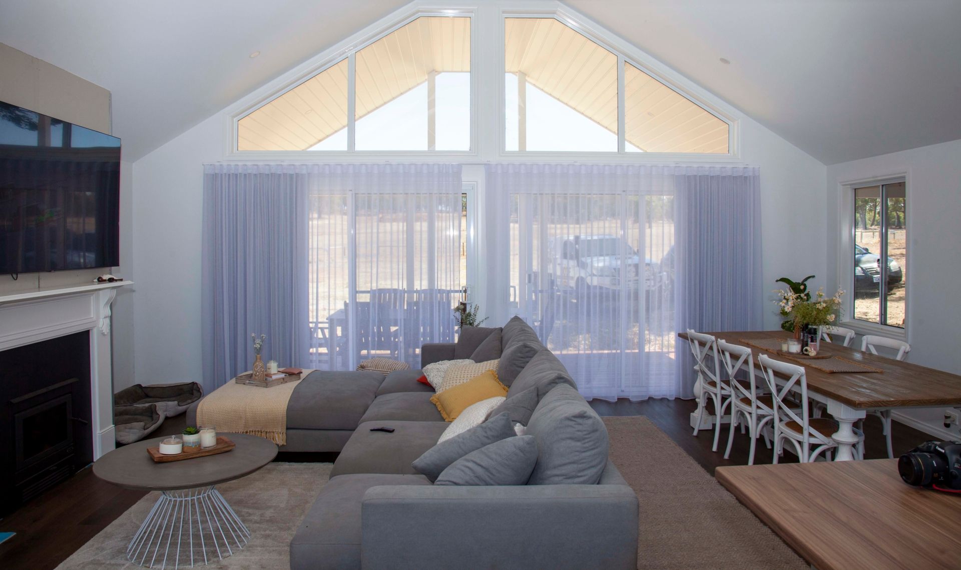 Sheer curtains across tall windows in an open-plan living room