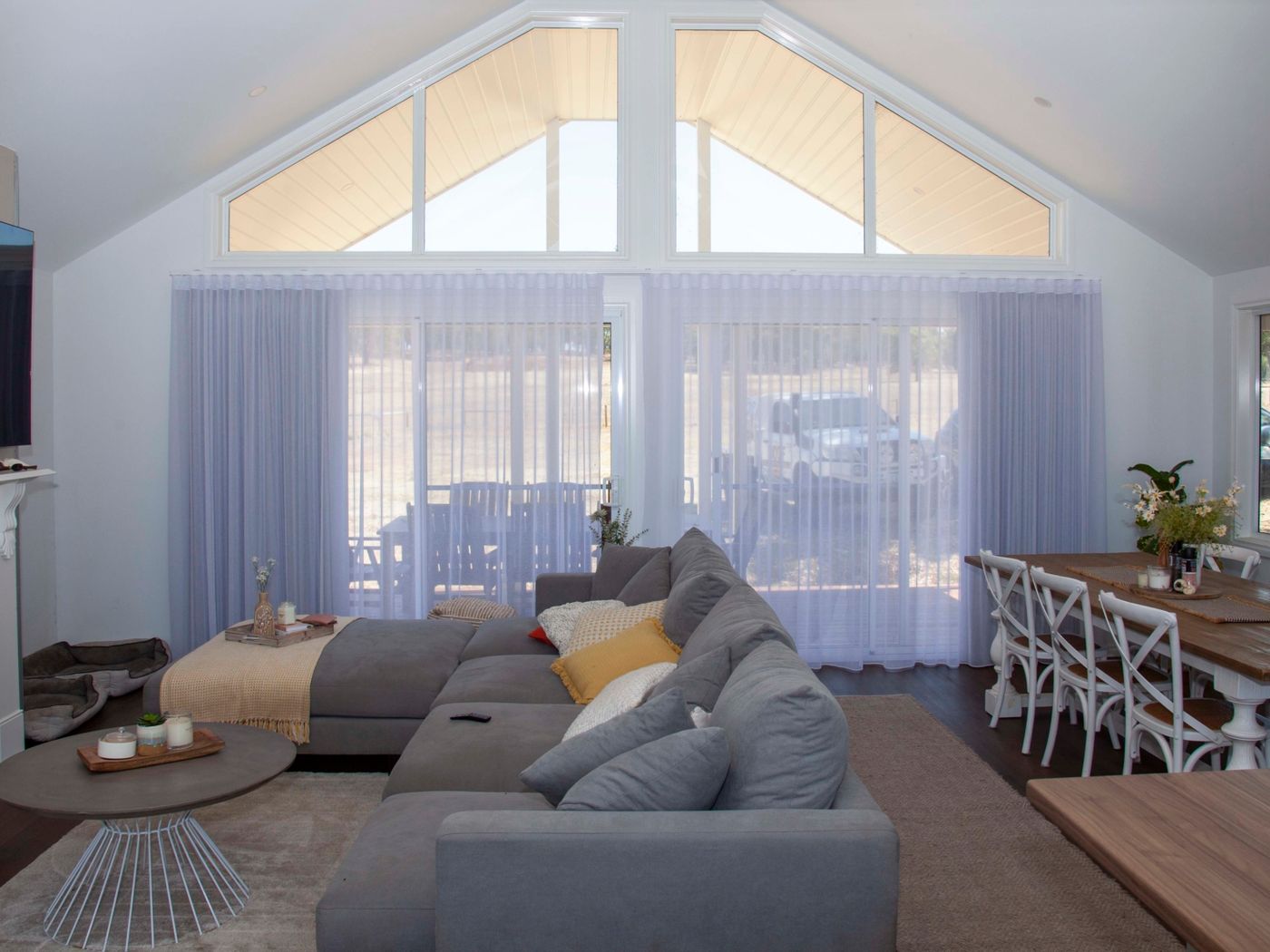 Sheer curtains across tall windows in an open-plan living room