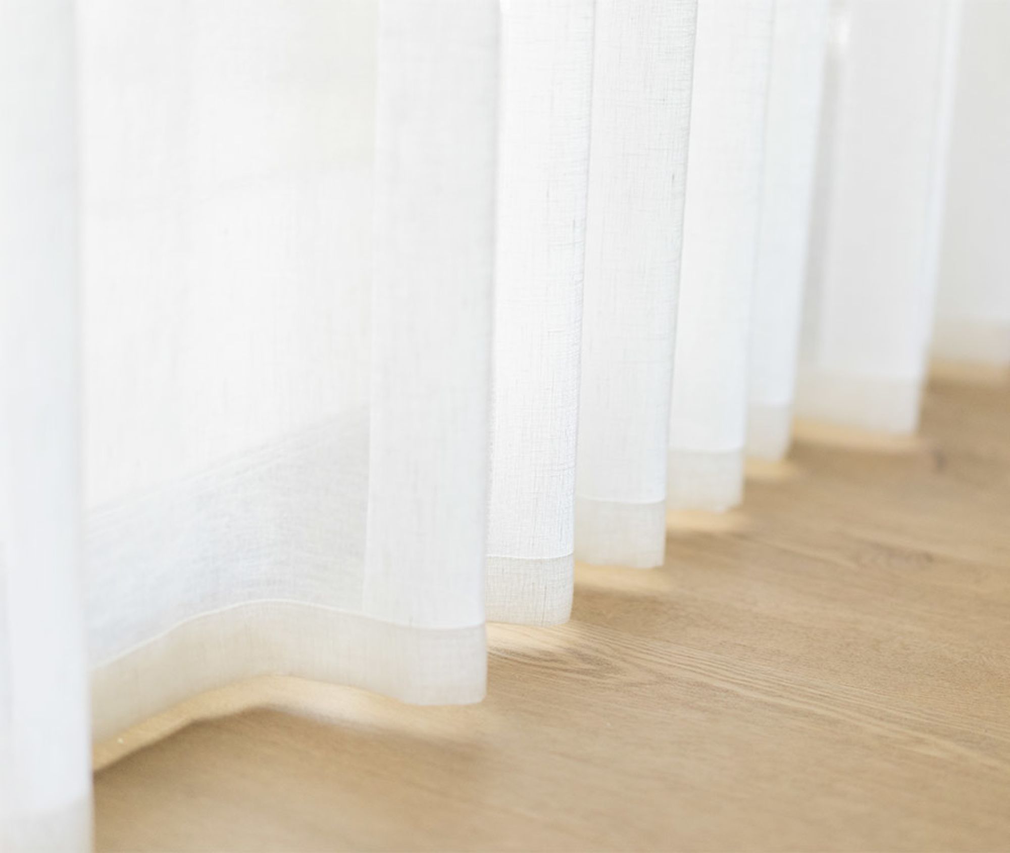 White linen sheer curtains falling to a timber floor