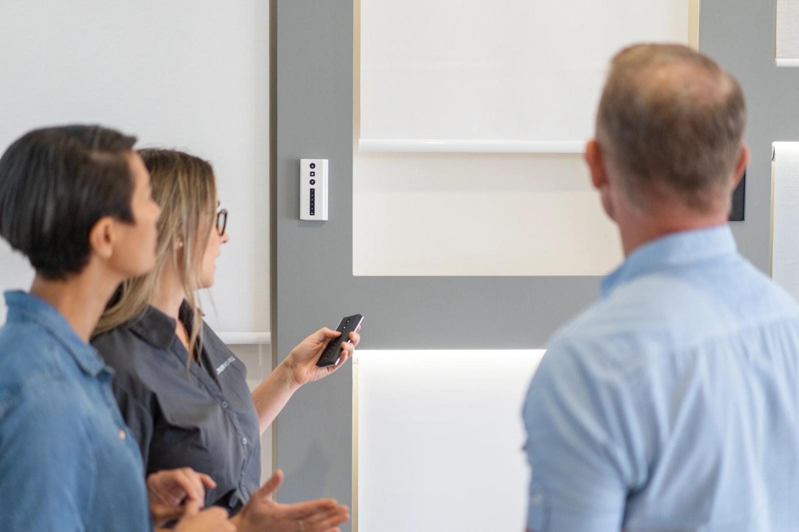 Curtain World consultant demonstrating a motorised blind remote to customers in the showroom
