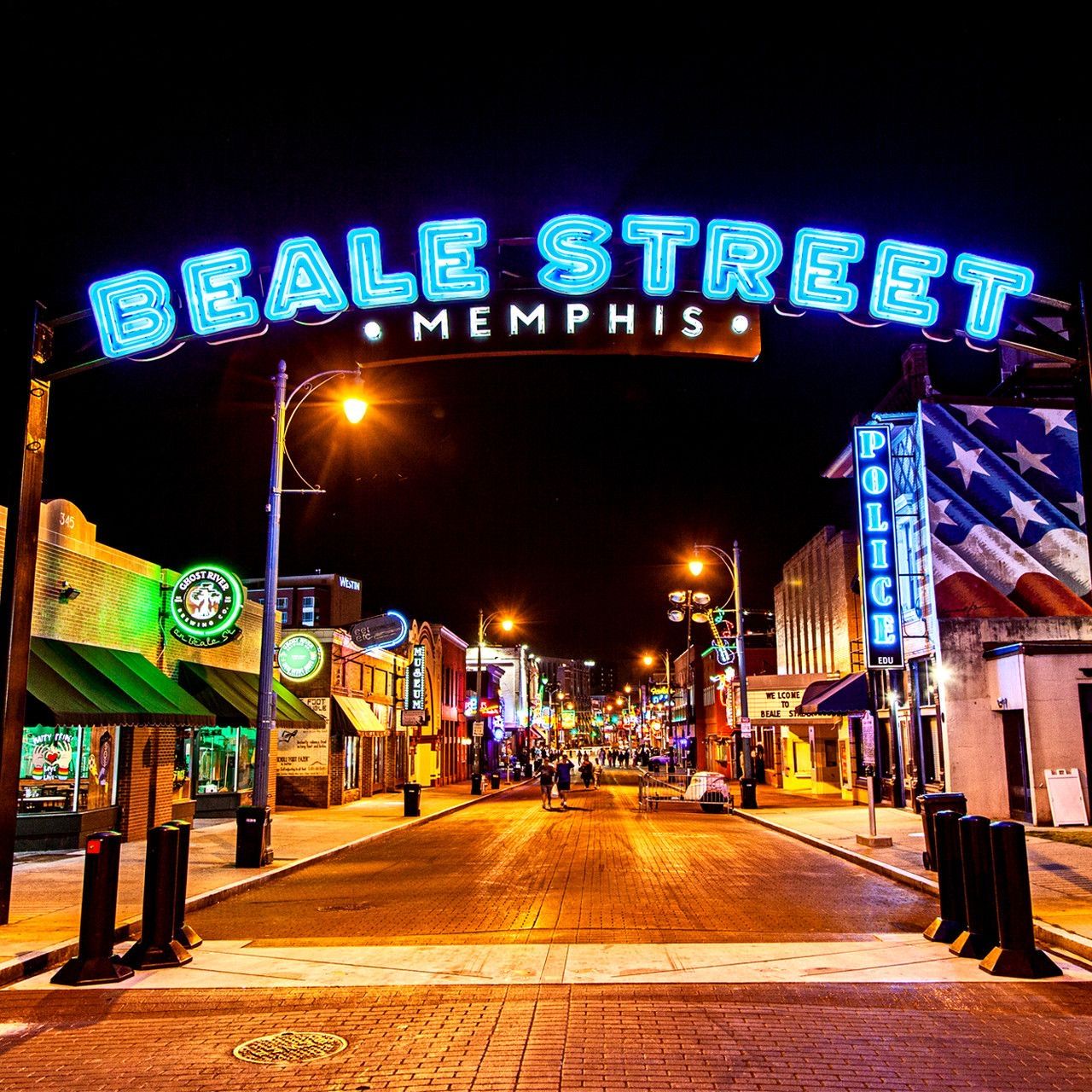 The entrance of Beale Street in Memphis, lit up at night - looking down a brick walk way with neon lights down the walk