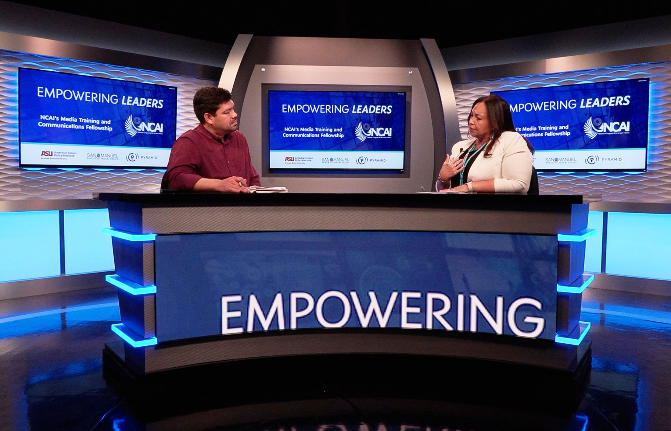 Two indigenous leaders in a newsroom practicing an interview