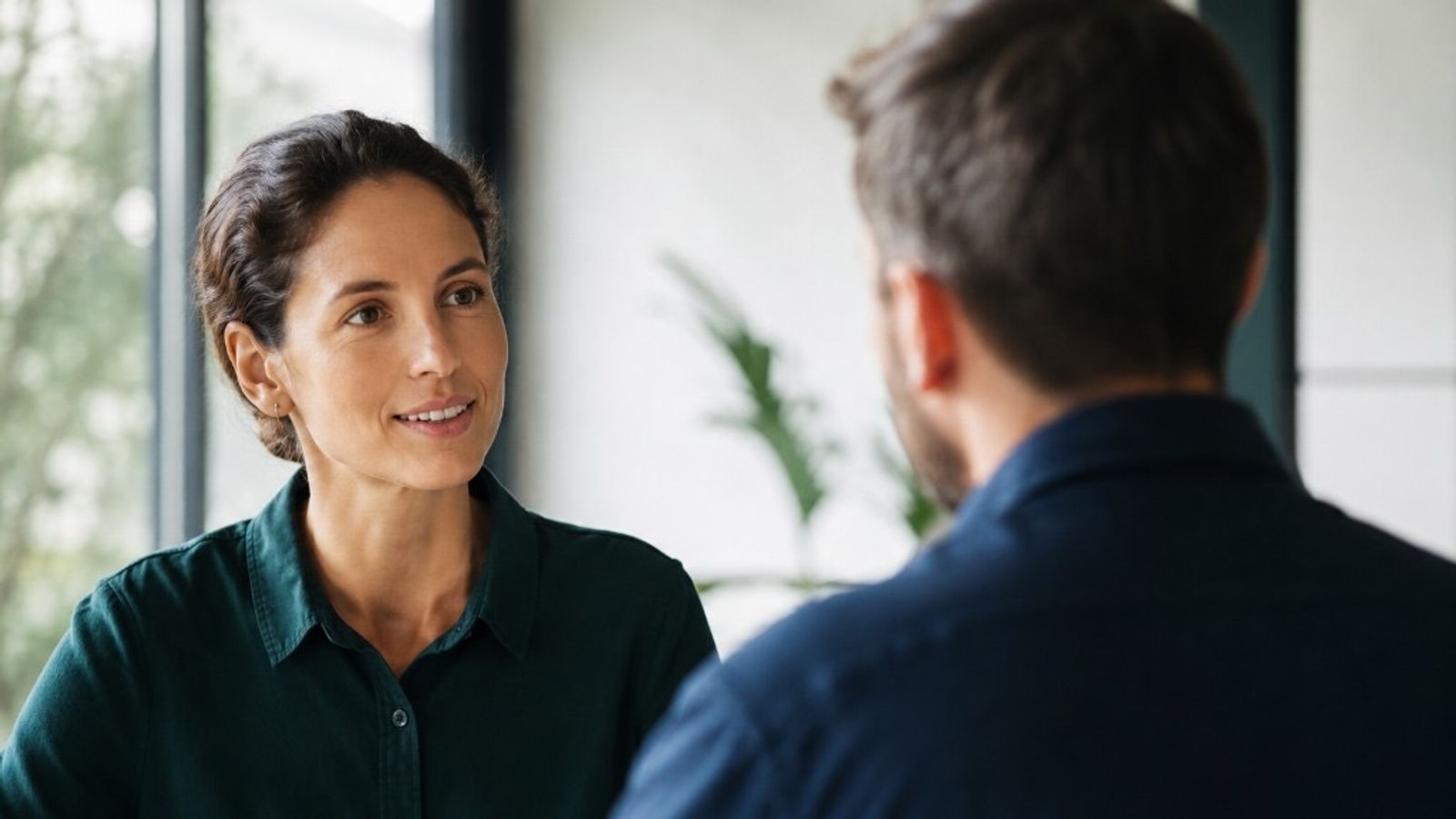Two professionals in a bright office having a calm, collaborative conversation about a business matter