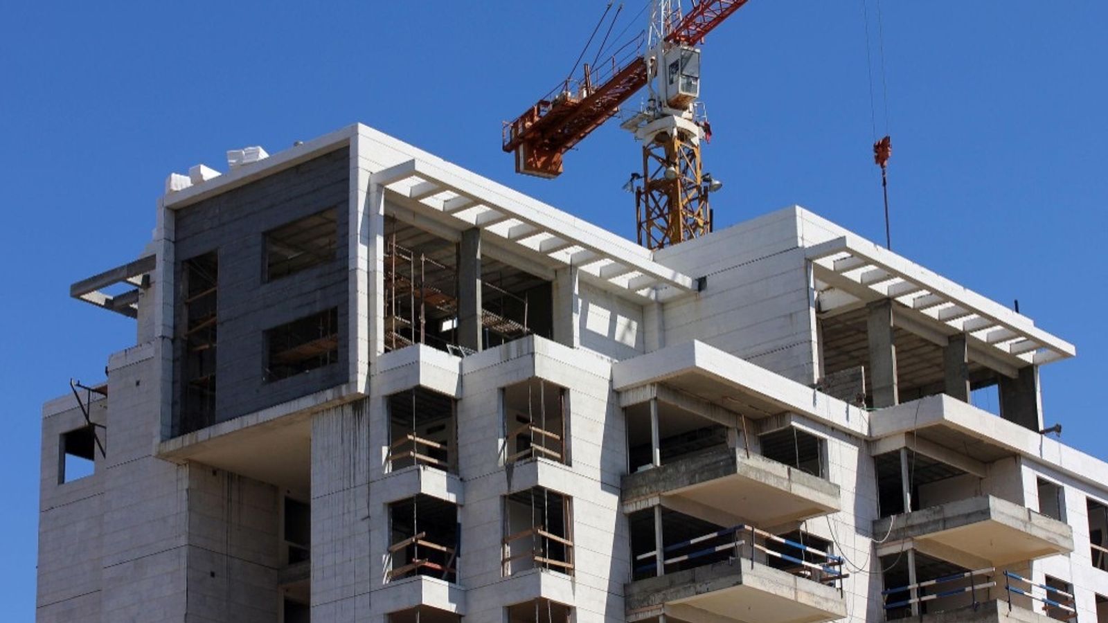 A multi-story building under construction with a tower crane, symbolizing a large project billed in stages through progress invoicing.