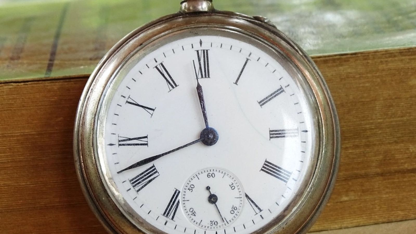 Antique pocket watch on an old book, symbolizing payment deadlines and time