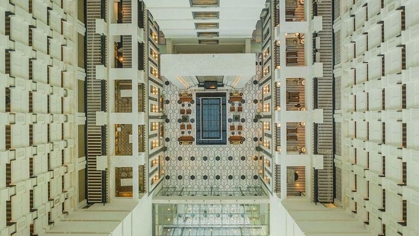Bird's-eye view of a modern multi-story building atrium with symmetrical balconies and a patterned lobby floor, symbolizing the structured overview financial statements provide