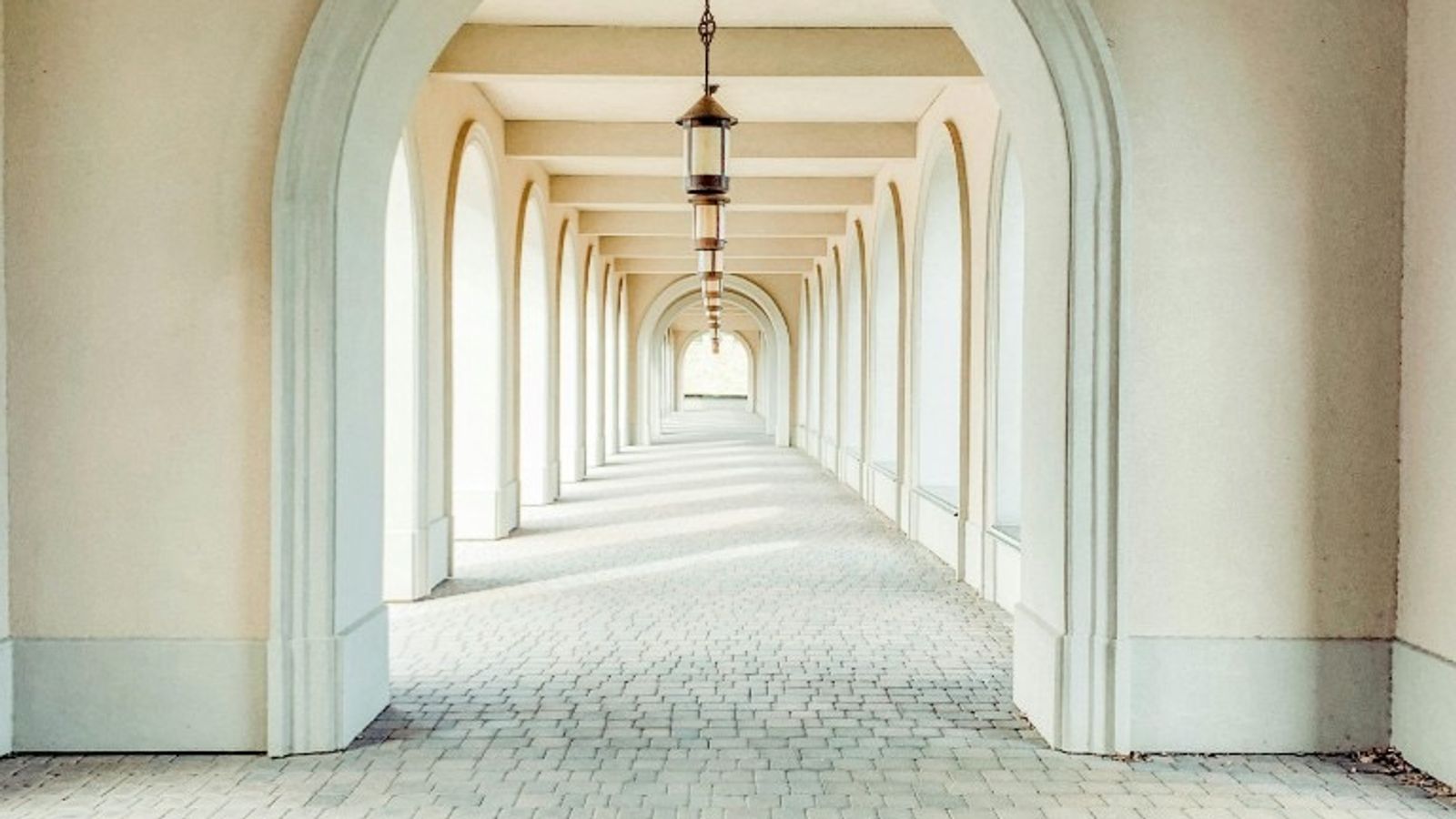 Symmetrical arched corridor with repeating vaults and pendant lanterns, suggesting two parallel paths leading to the same destination