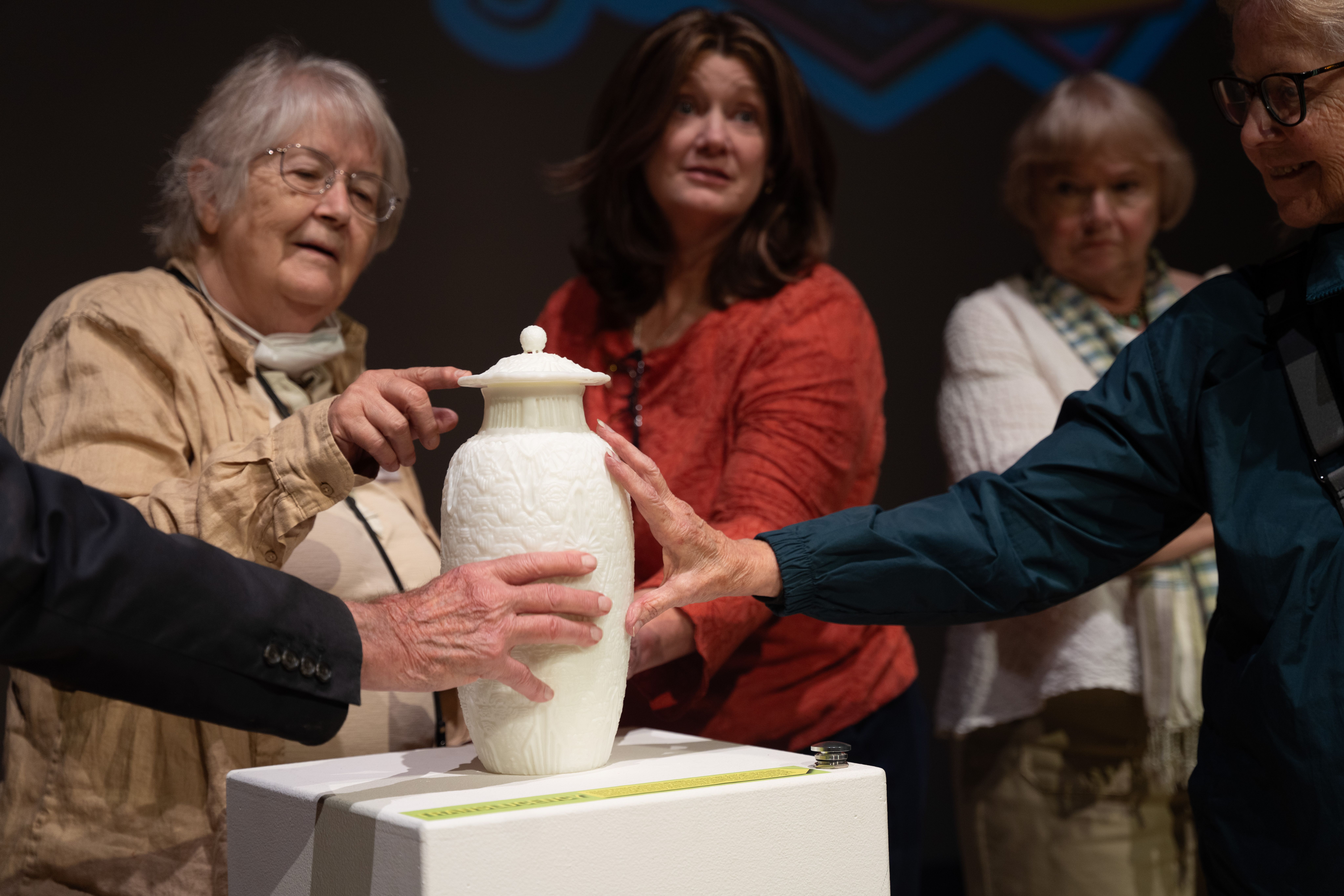People of all ages carefully touching and exploring the carved scarab details