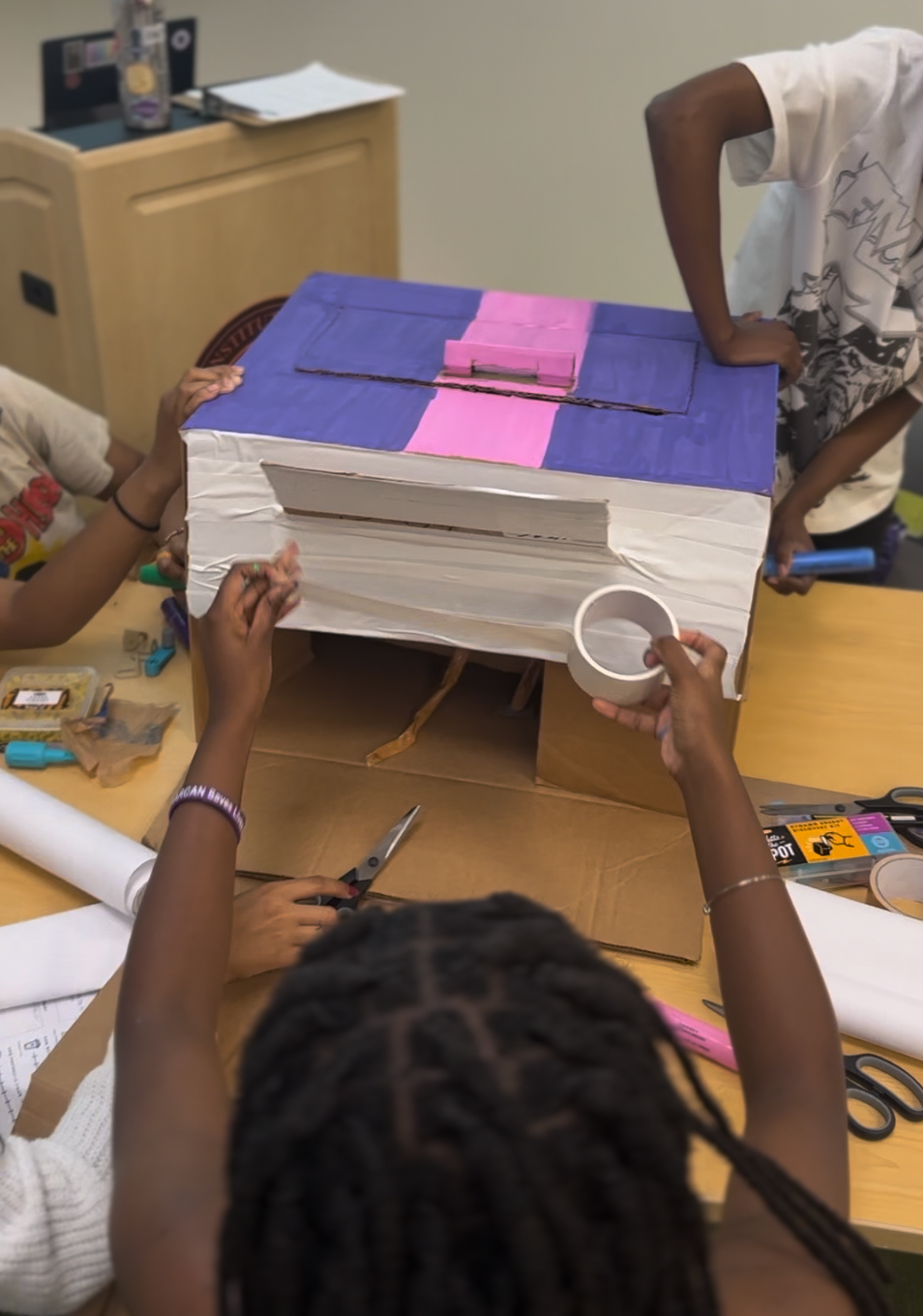 Students constructing early prototype with cardboard and circuit components