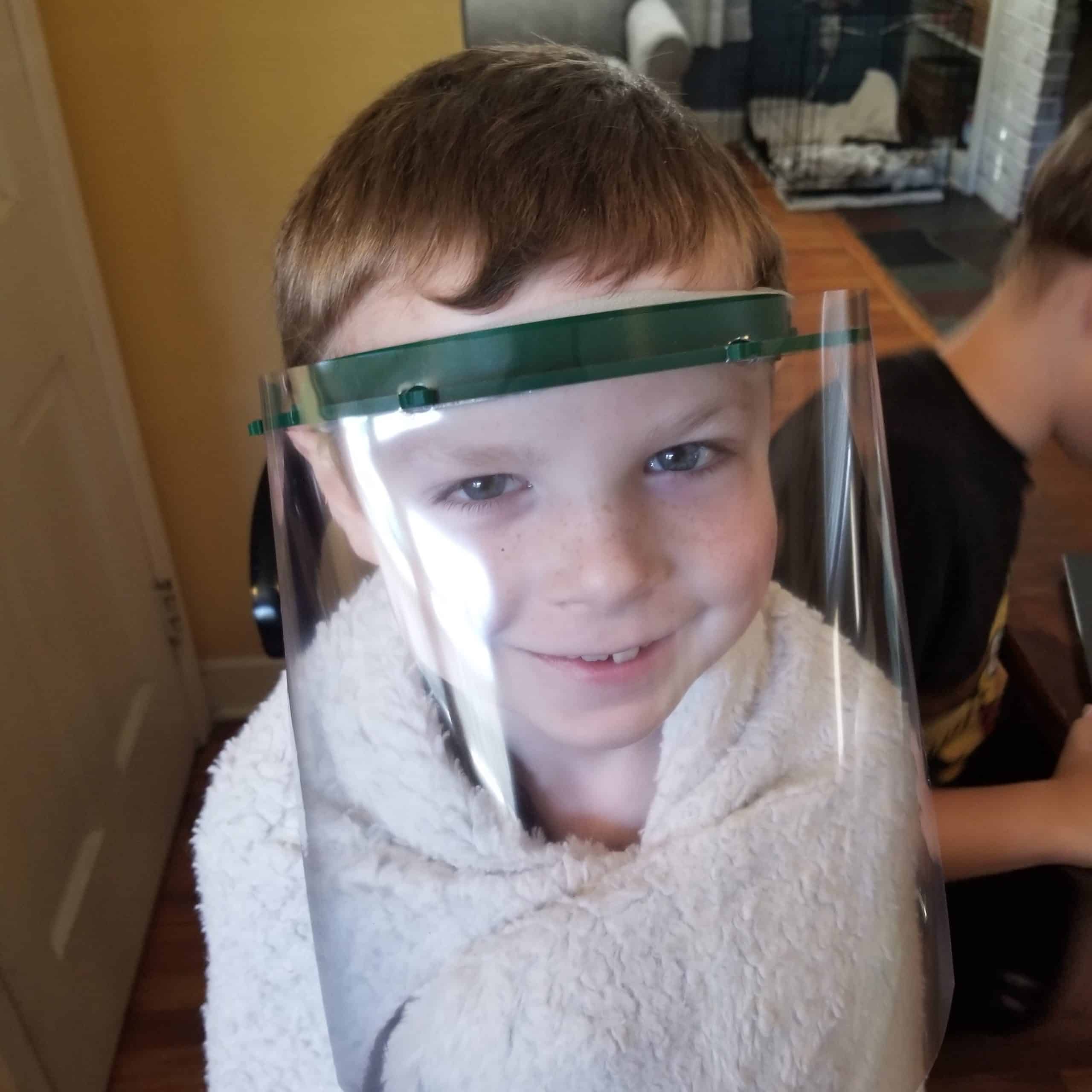 Katie's son modeling the child size face shield she created.
