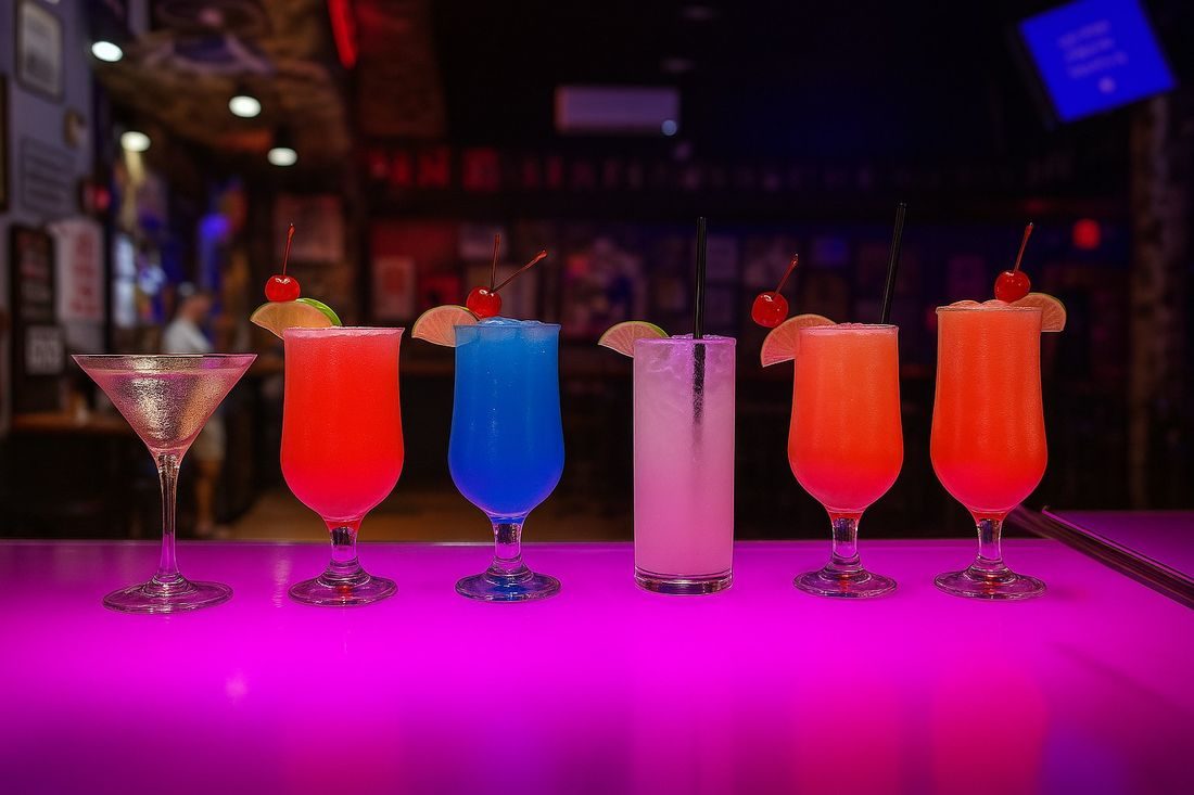 Row of bright cocktails lined up on the pink bar