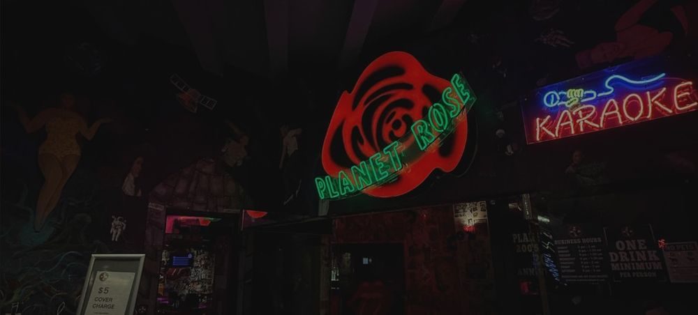 The Planet Rose and Karaoke neon signs glowing in the dark